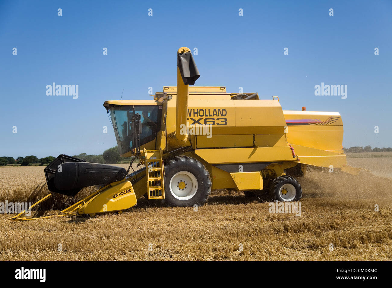 New Holland TX63 combine harvester peignant l'orge dans le Norfolk, Royaume-Uni contre un ciel d'été bleu Banque D'Images