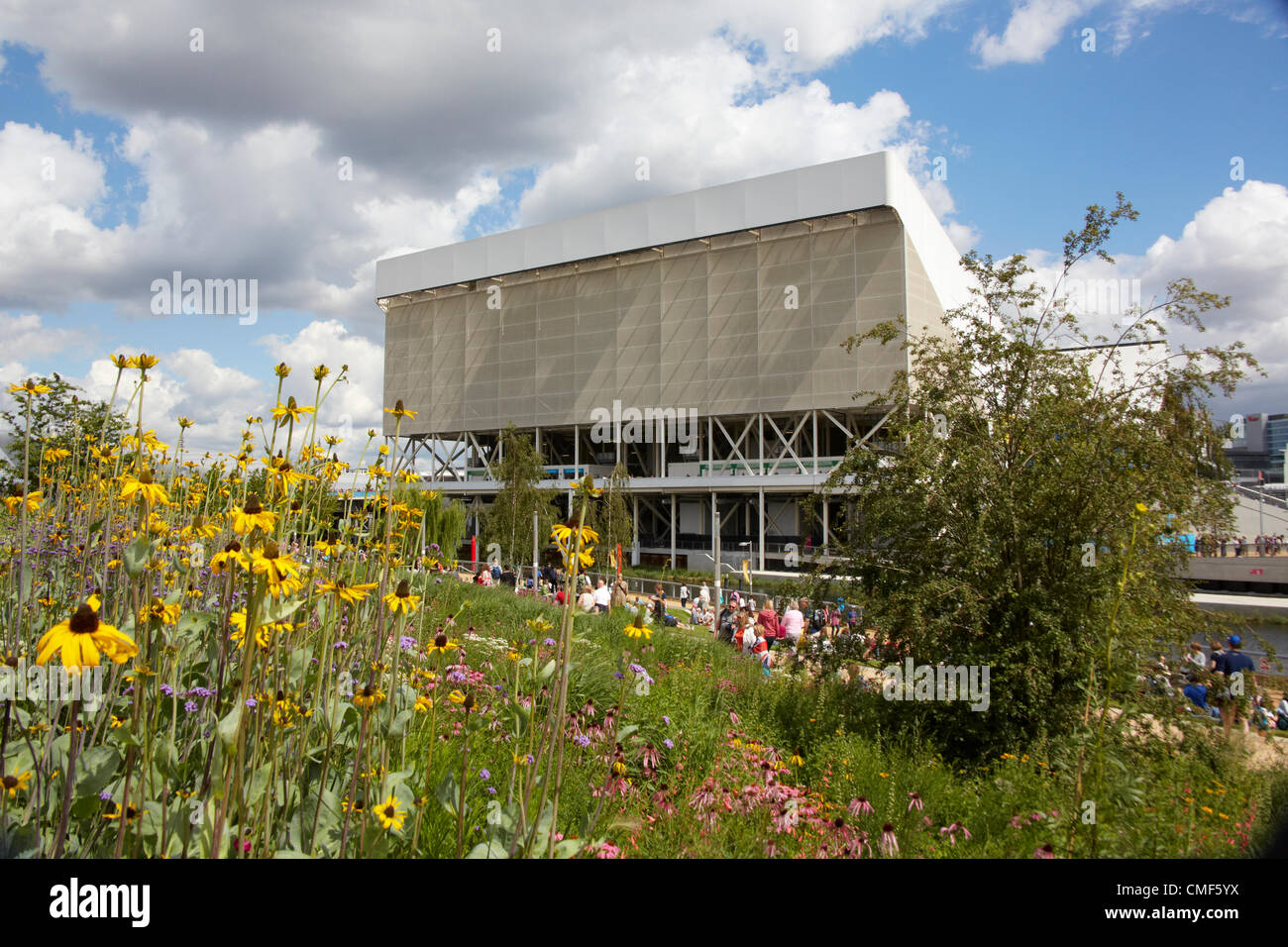 Le Centre aquatique au-delà wildflower meadow sur une journée ensoleillée au parc olympique, site des Jeux Olympiques de 2012 à Londres, Stratford London E20, Royaume-Uni Banque D'Images