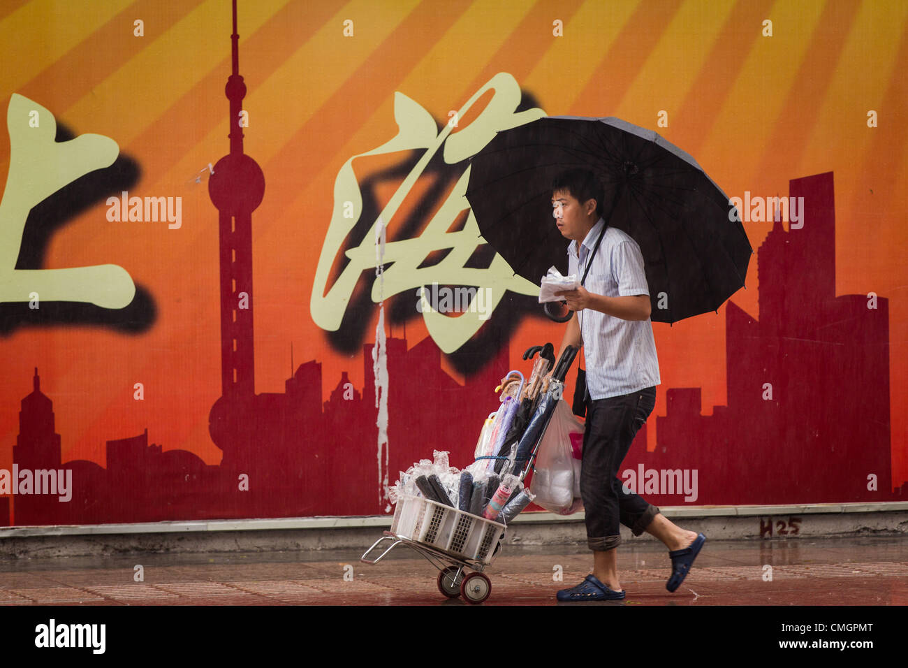 Un parapluie vendeur hi hawks le long de la rue Nanjing marchandises comme le typhon Haikui a atteint les côtes de l'est de la Chine d'effectuer vie de 23 millions de personnes dans le centre des affaires de Shanghai le 8 août 2012 à Shanghai, Chine. Banque D'Images