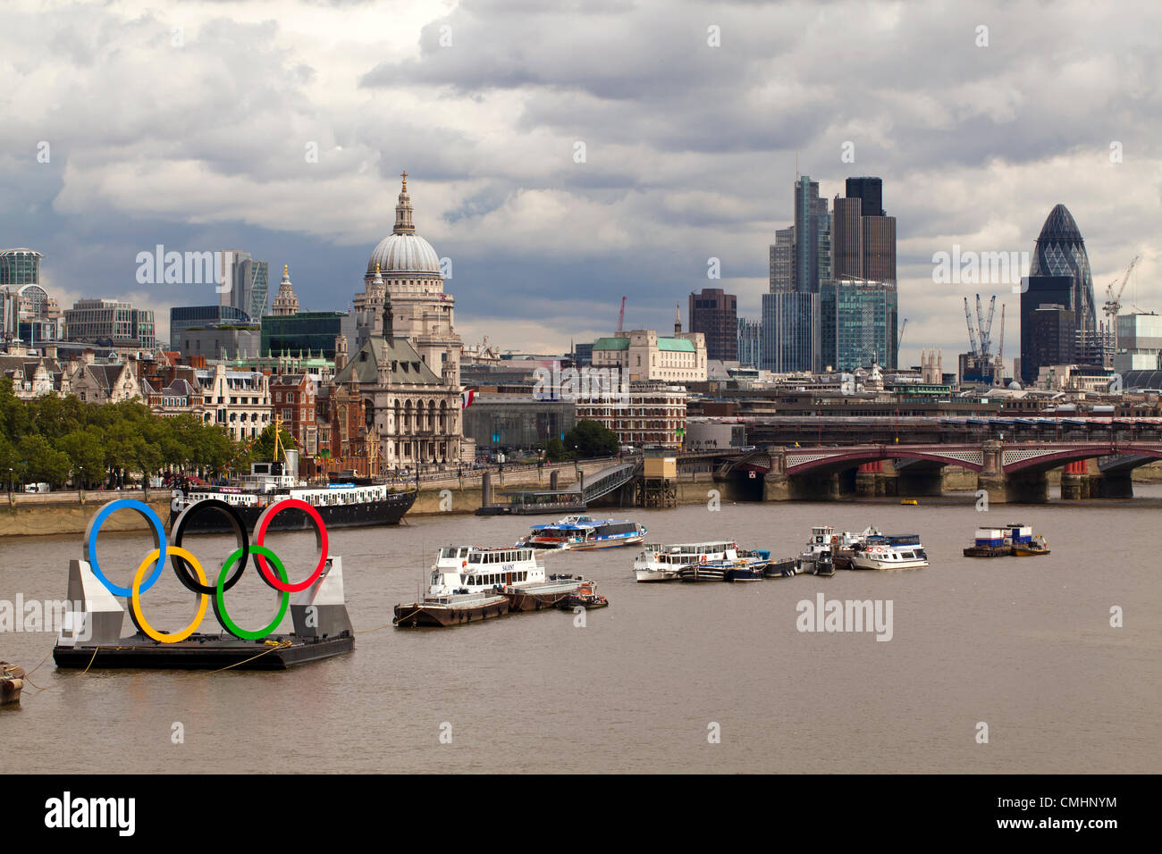 Les anneaux olympiques amarré le long de la Tamise, Londres illustré avec un fond de Londres y compris le Gherkin et la Cathédrale St Paul. Banque D'Images