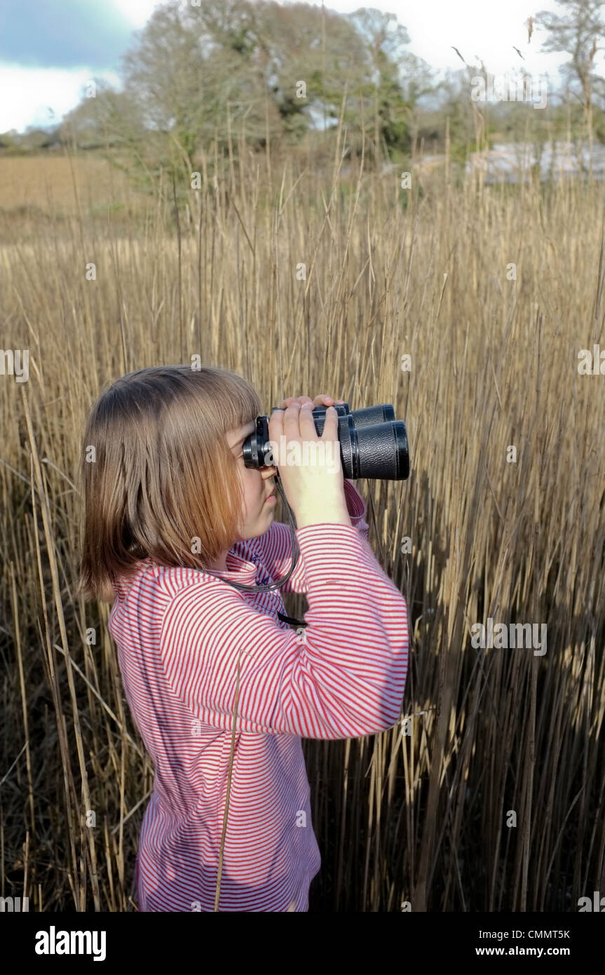 Une fillette de 9 ans à la recherche pour les oiseaux à travers une paire de jumelles Banque D'Images