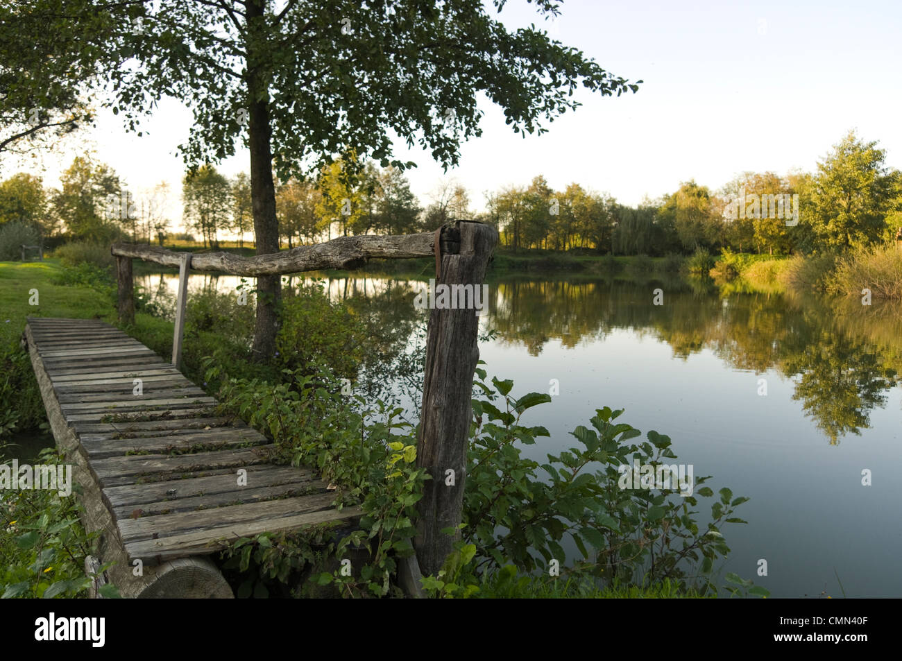 Vue paysage sur petit lac et pont de bois au début de l'été le coucher du soleil. Banque D'Images