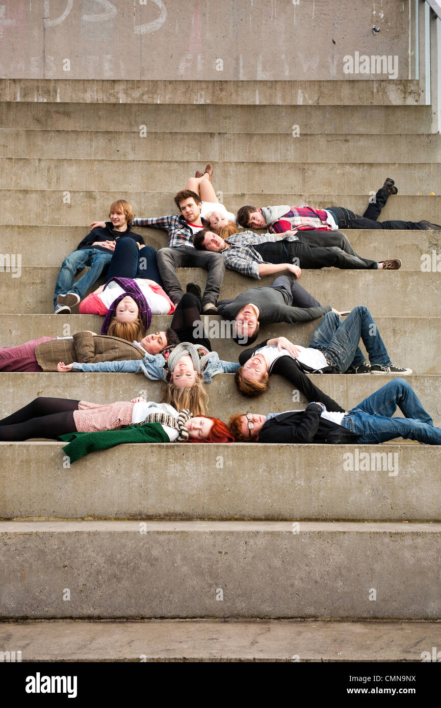Un groupe mixte de jeunes teenage Aberystwyth University college student amis ensemble, c'est effondré sur des mesures concrètes, UK Banque D'Images