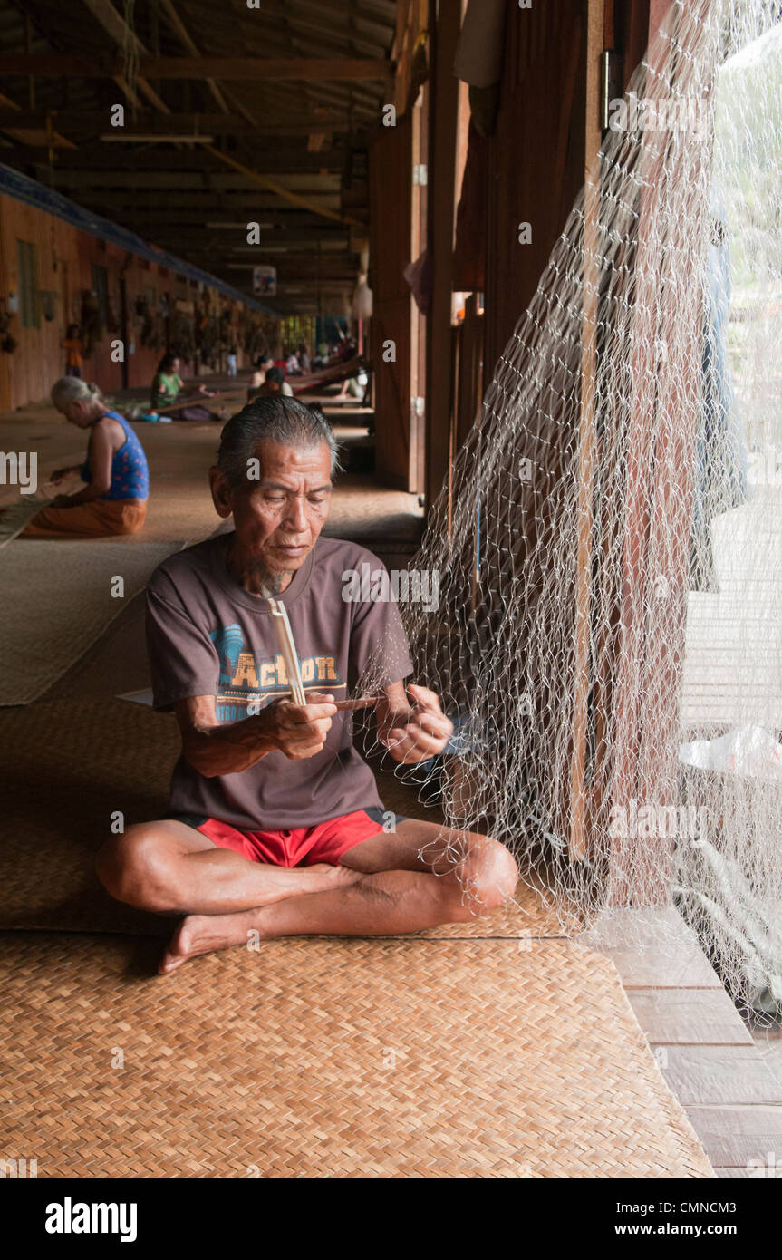 Iban longhouse chef raccommode ses filets de pêche à la Nanga Sumpa longhouse au Sarawak, Bornéo, Malaisie Banque D'Images
