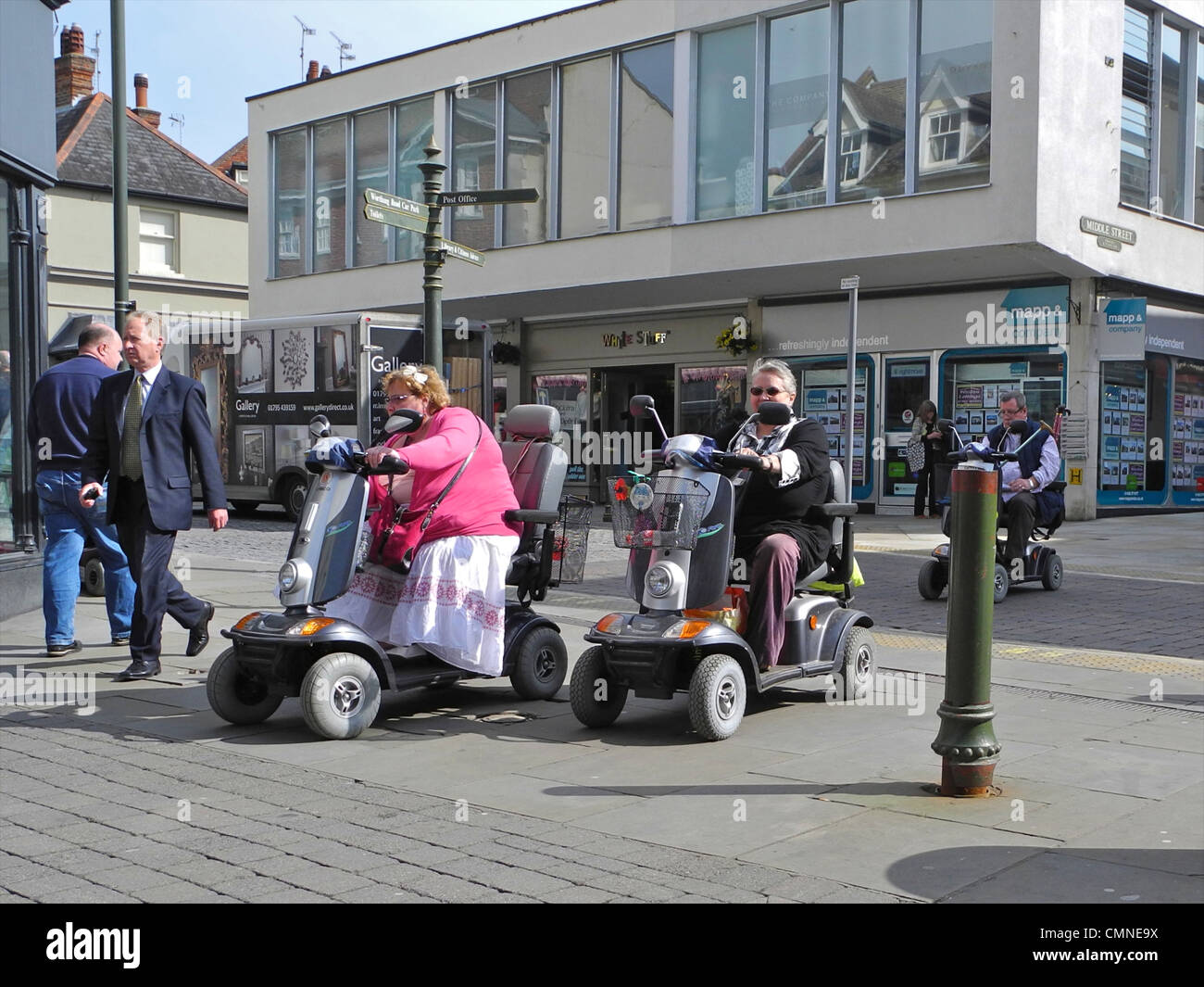 Les personnes utilisant un fauteuil motorisé dans un centre commercial, centre-ville. Cette image est d'ordre rédactionnel SEULEMENT ET NE DOIT PAS ÊTRE UTILISÉE D'UNE FAÇON QUI DÉNIGRE LES UTILISATEURS DES TRIPORTEURS c'est à West Street, Horsham, Sussex de l'Ouest. Banque D'Images