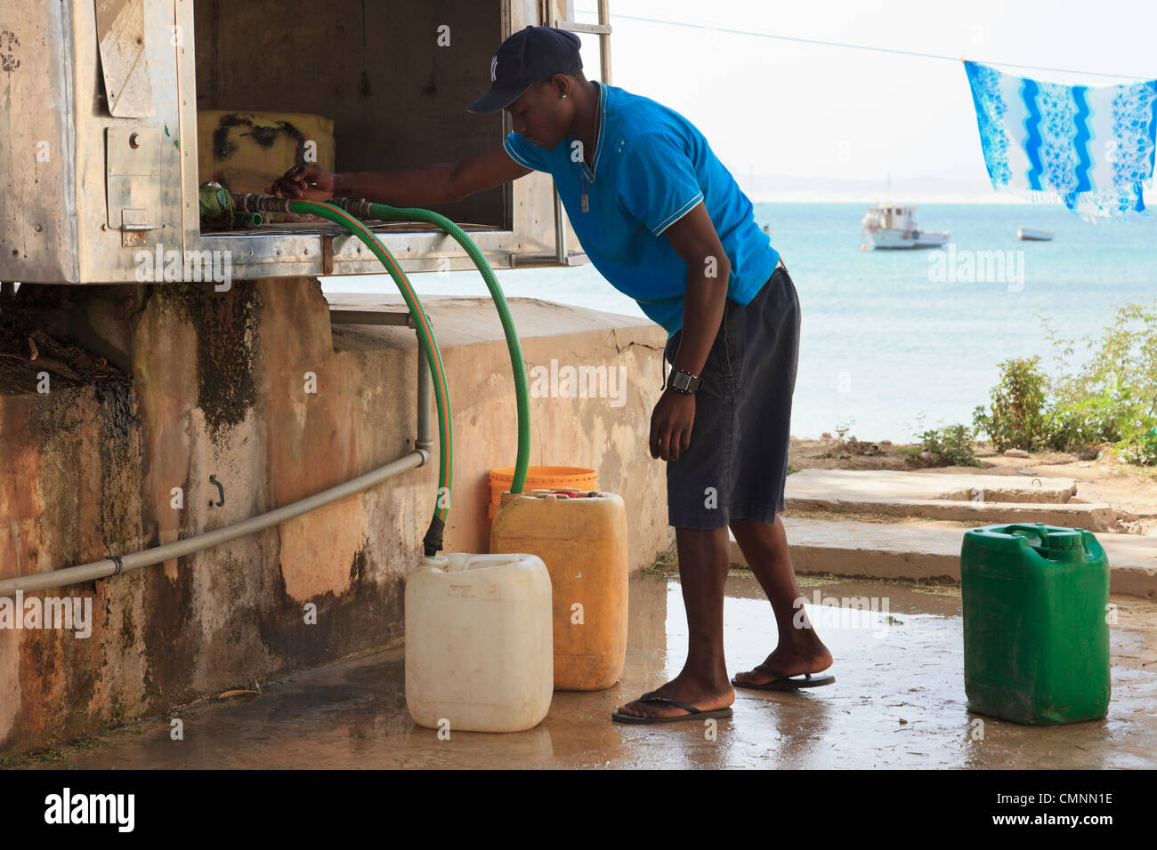 L'homme local avec des conteneurs pour la collecte de l'eau potable dessalée à partir d'un bowser. Sal Rei, Boa Vista, Cap Vert Banque D'Images