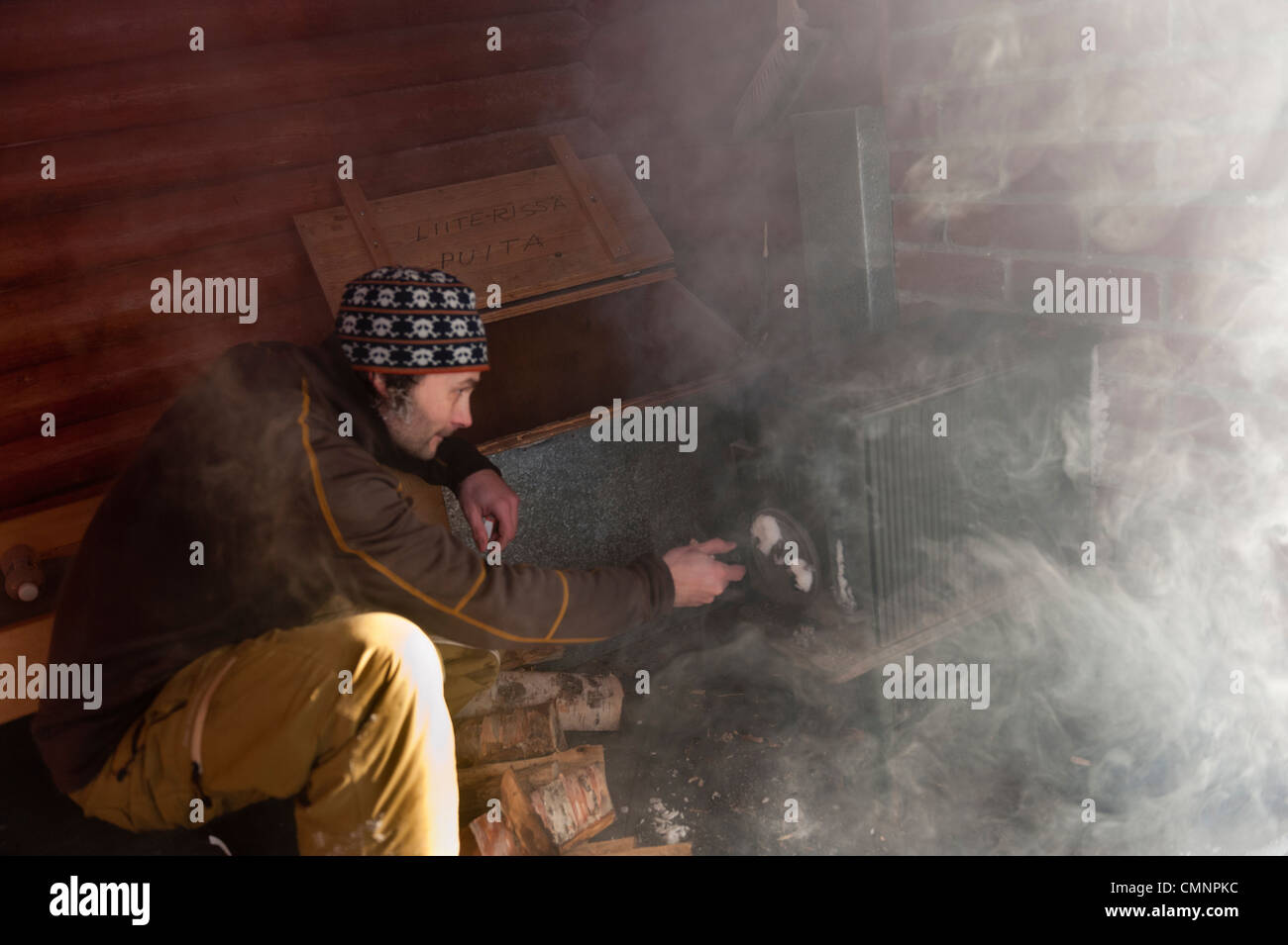 Un homme lançant un incendie dans une cabane à Kittilä, Laponie finlandaise. Banque D'Images