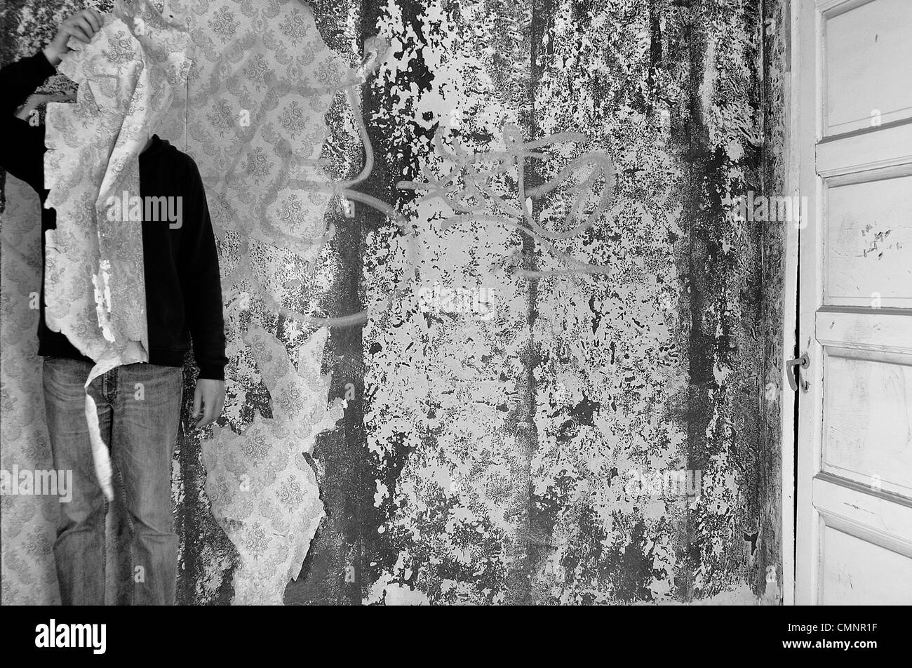 La figure masquée avec papier peint déchiré abandonné dans l'intérieur. Noir et blanc. Banque D'Images