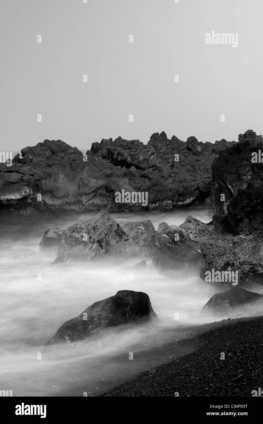 Pierres et surf. Une longue exposition cliché pris à la Big Island, Hawaii, USA sur une plage de galets dans la matinée. Banque D'Images