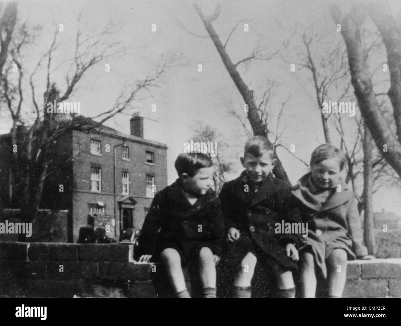 Bushbury Bushbury, Hill Farm, vers 1940. Trois enfants assis sur un mur en face de la construction de la ferme. À ce point de Banque D'Images