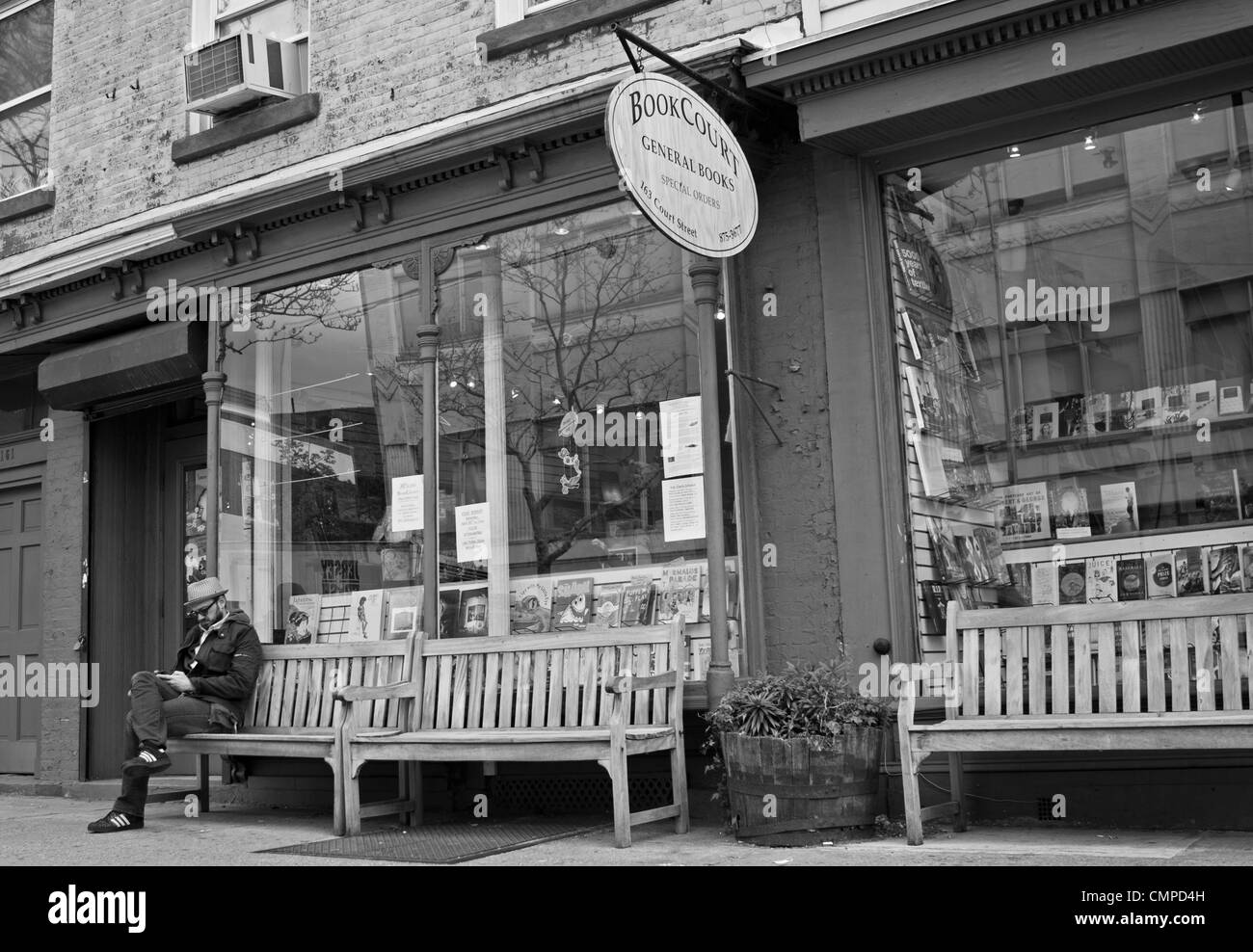 Un homme est assis sur un banc à l'extérieur une librairie dans le quartier de Cobble Hill de Brooklyn, New York. Banque D'Images