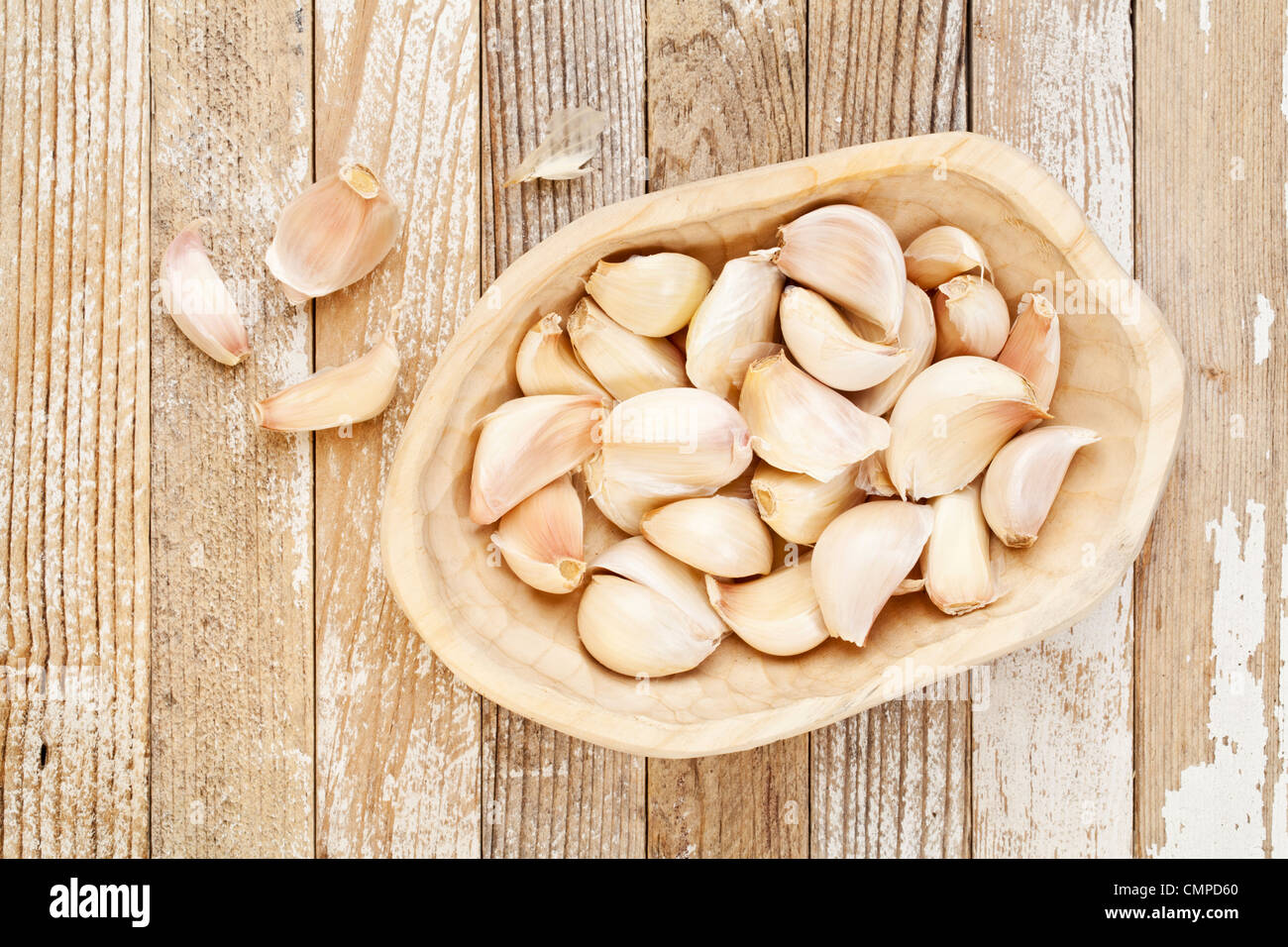 Gousses d'ail dans un bol en bois rustique contre grunge fond en bois peint Banque D'Images