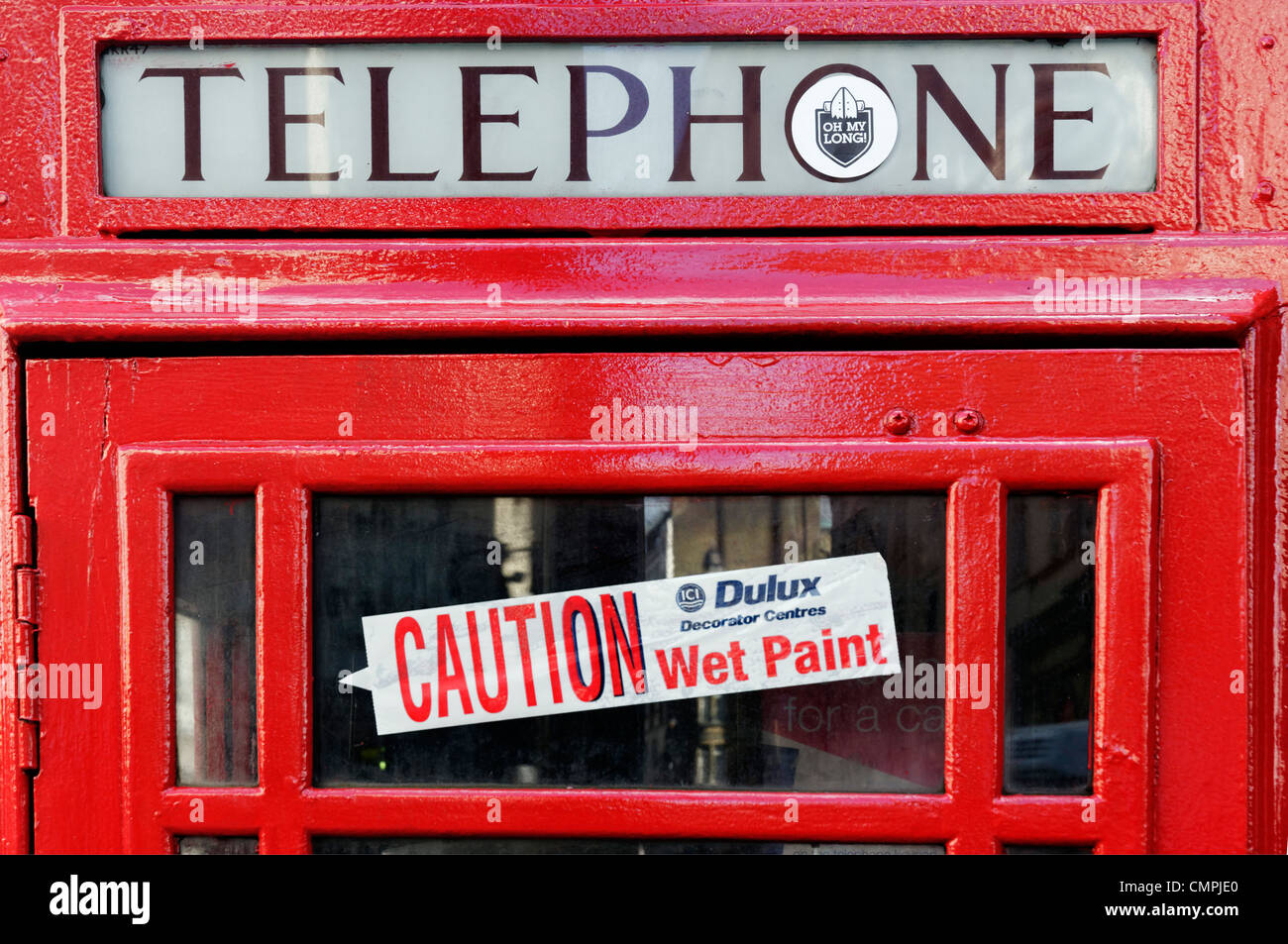 Une cabine téléphonique publique rouge avec une "attention - wet paint' dans la fenêtre autocollant Banque D'Images