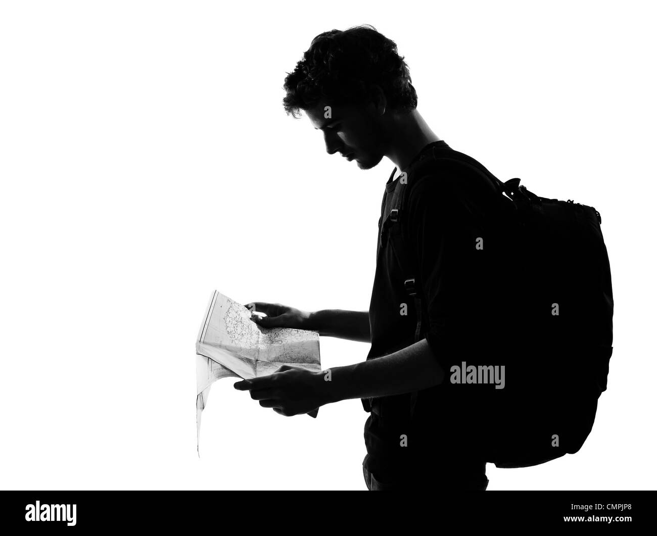 Jeune homme backpacker traveler looking at map silhouette en studio isolé sur fond blanc Banque D'Images
