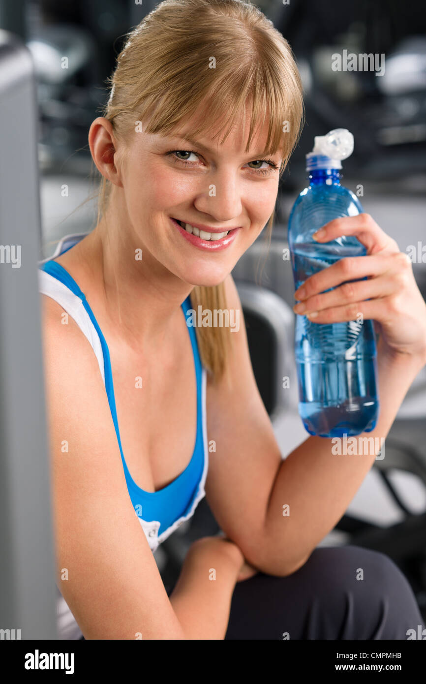 Smiling woman boire de l'eau détendez-vous au centre de remise en forme de la machine de poids Banque D'Images