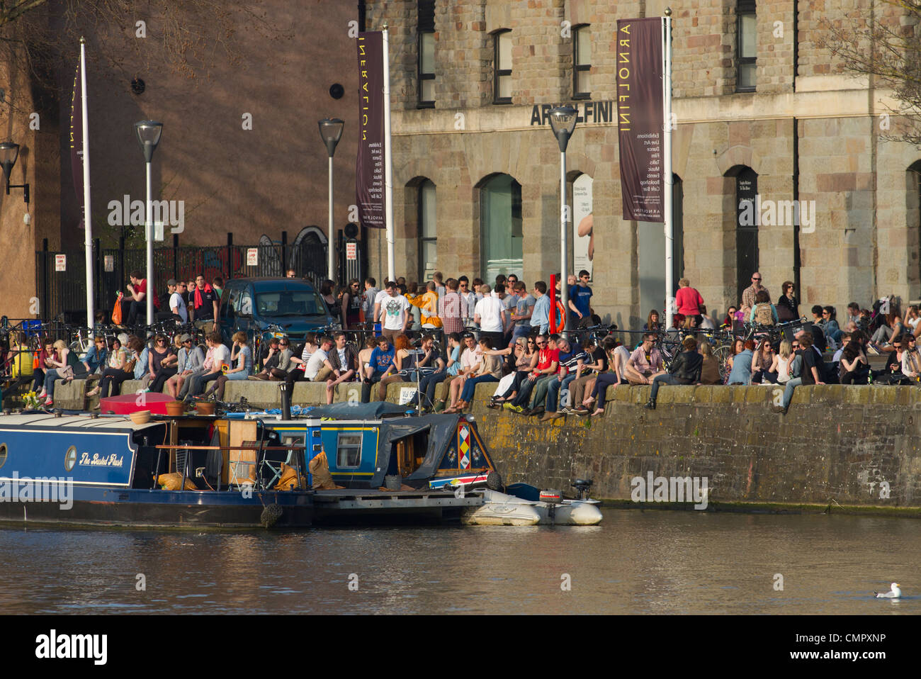 Les gens profiter du soleil sur l'harbourside en dehors de la galerie Arnolfini à Bristol. Le centre est un hotspot culturelle pour la ville. Banque D'Images