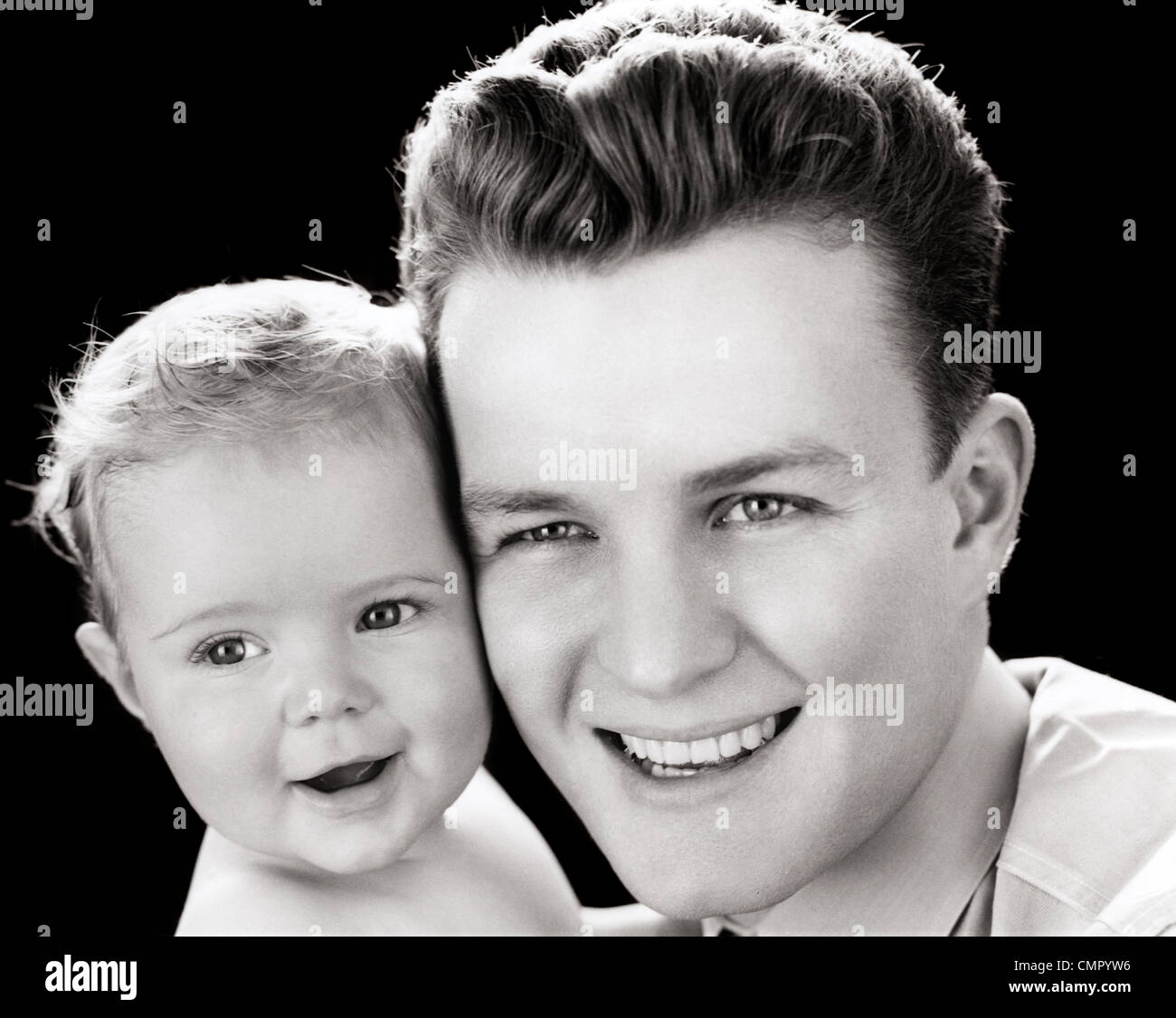 1940 PORTRAIT OF SMILING FATHER HOLDING BABY DAUGHTER TO CHEEK Banque D'Images