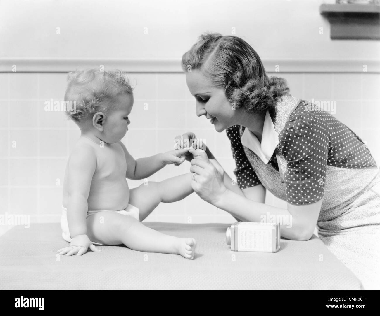 1930 MOTHER TOUCHING BABY ORTEILS DOIGTS Ce petit cochon COMPTINE Banque D'Images