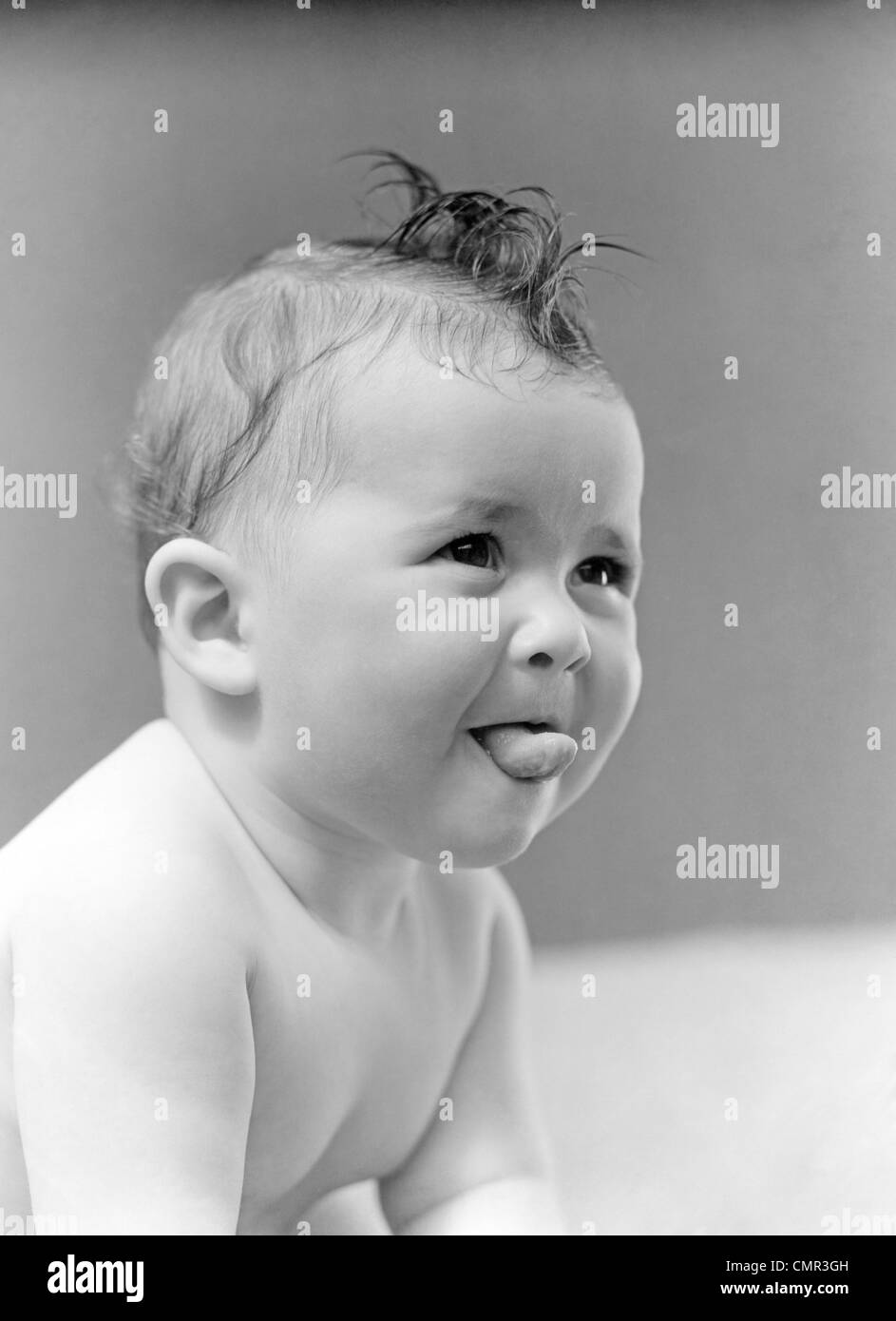 1940 CUTE BABY STICKING OUT TONGUE STUDIO Banque D'Images