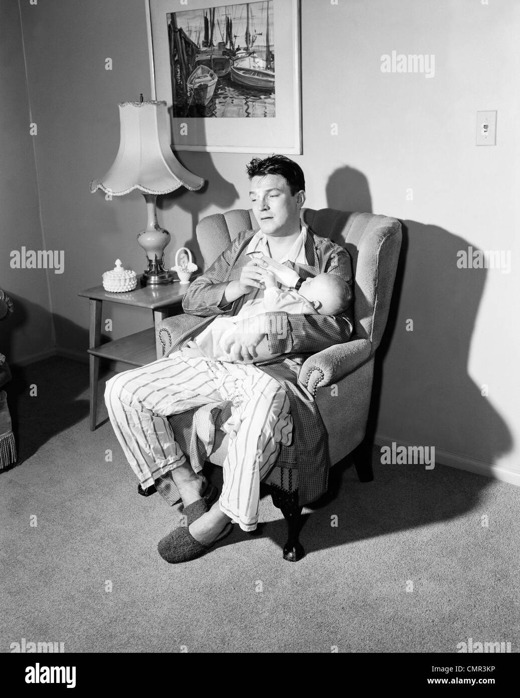 1950 Père fatigué de donner le biberon à l'alimentation de nuit Banque D'Images