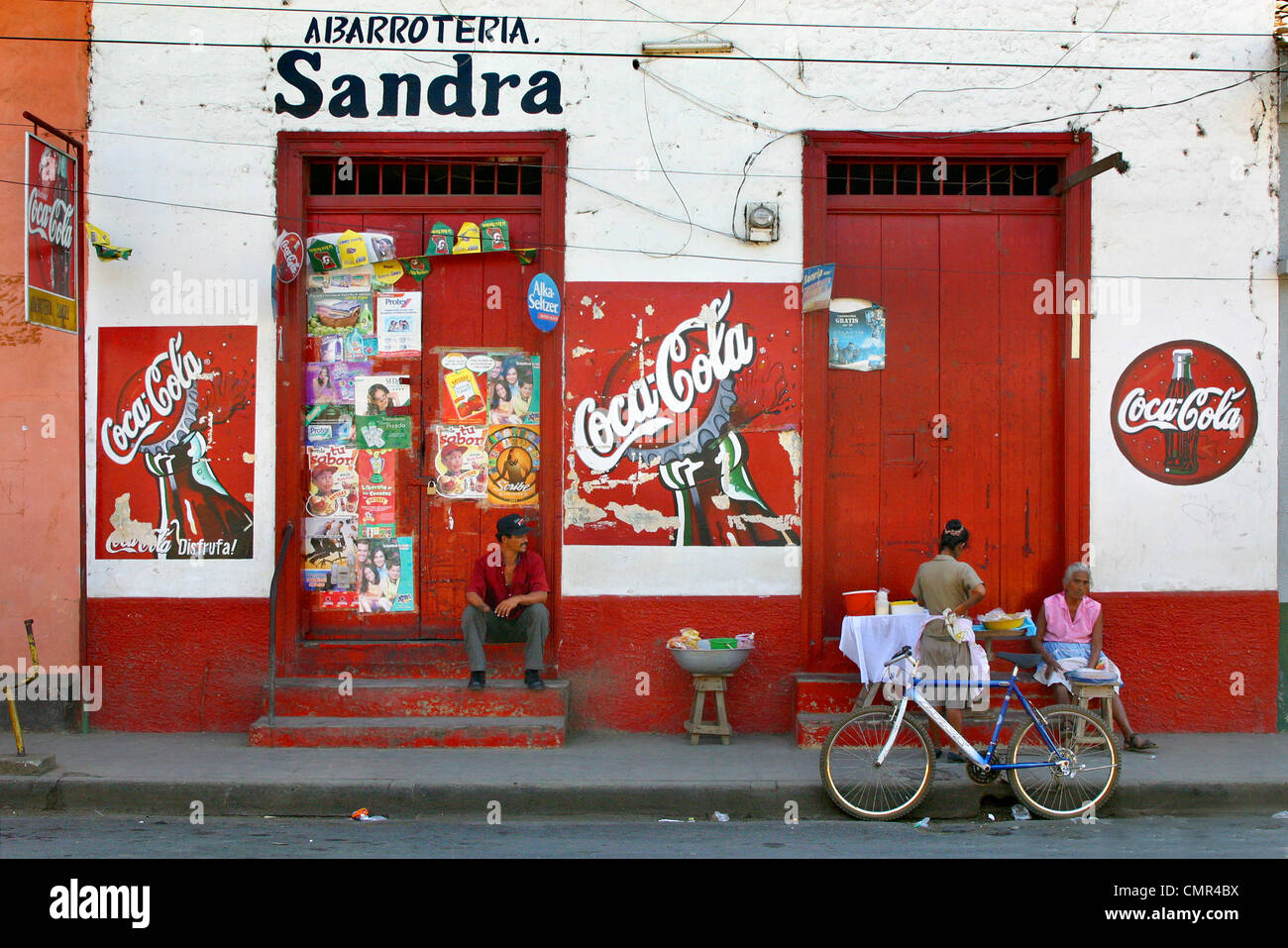 Leon, Nicaragua, scène de rue avec coca cola signes et des publicités et des affiches collées sur les portes rouges. Banque D'Images