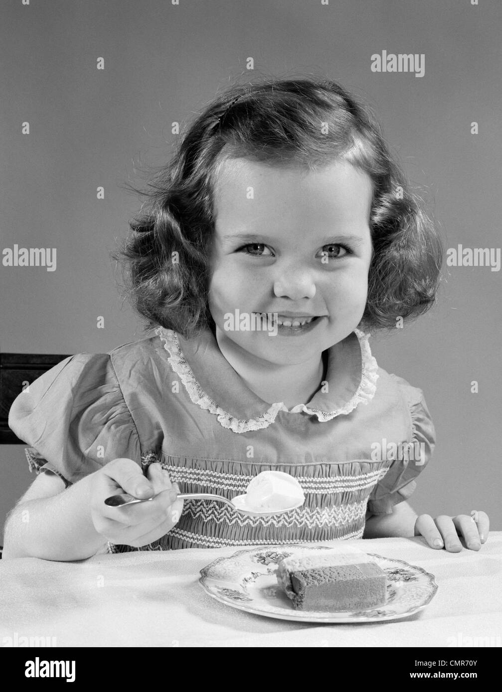 1950 LITTLE GIRL EATING ICE CREAM SMILING Banque D'Images