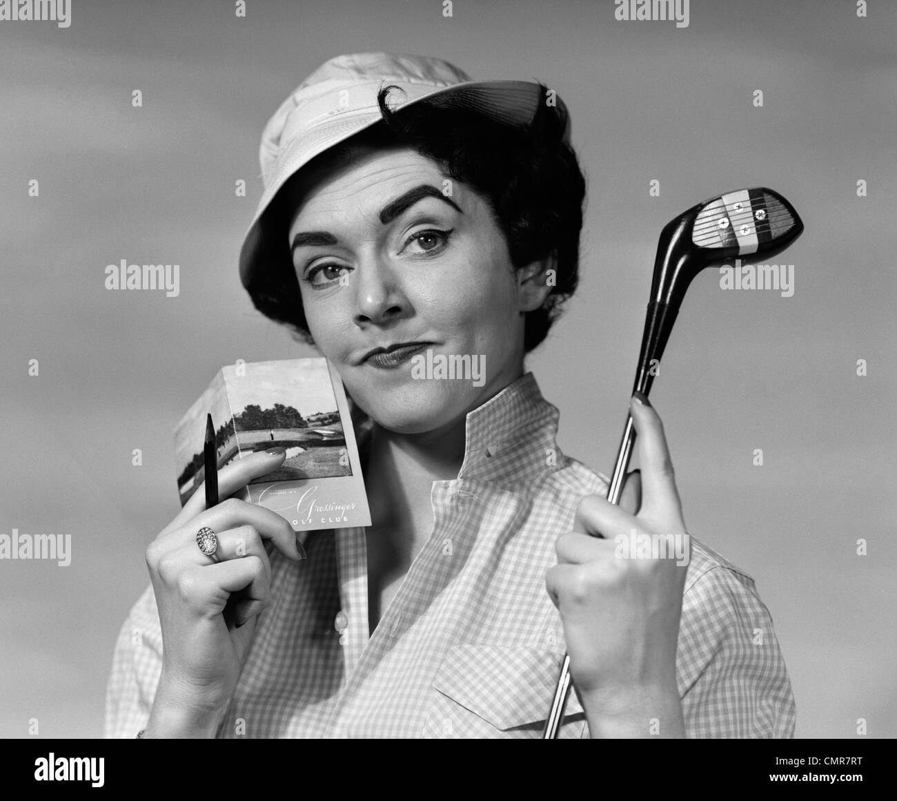 Années 1950 Années 1960 PORTRAIT WOMAN IN HAT HOLDING GOLF CLUB & SCORECARD AVEC LOOK PERTURBÉ SUR LE VISAGE LOOKING AT CAMERA Banque D'Images