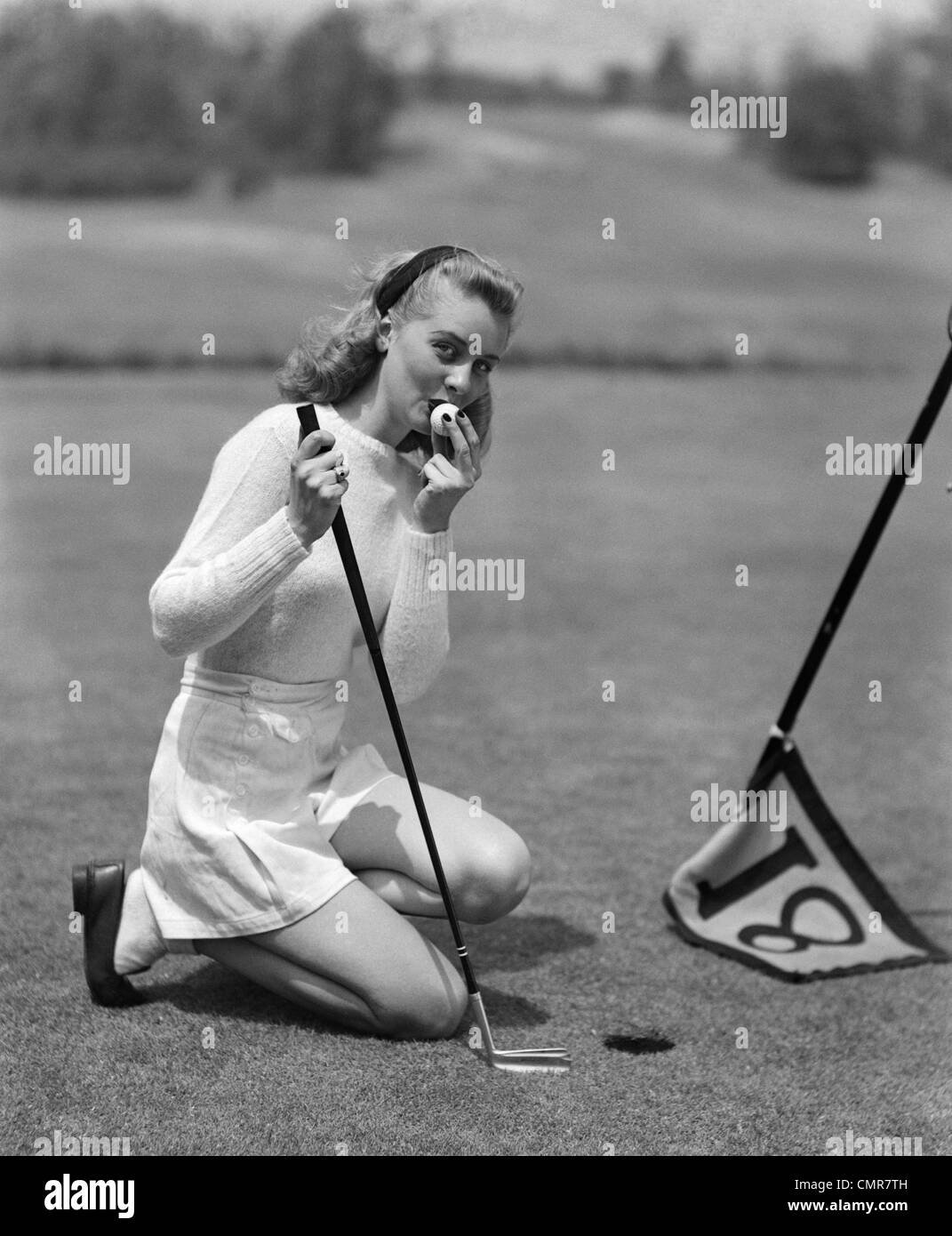 1950 femme agenouillée GOLFEUR PAR TASSE EN BLANC Chandail Sport & shorts à  la caméra à s'embrasser en balle de golf PUTT SUR 18e trou Photo Stock -  Alamy