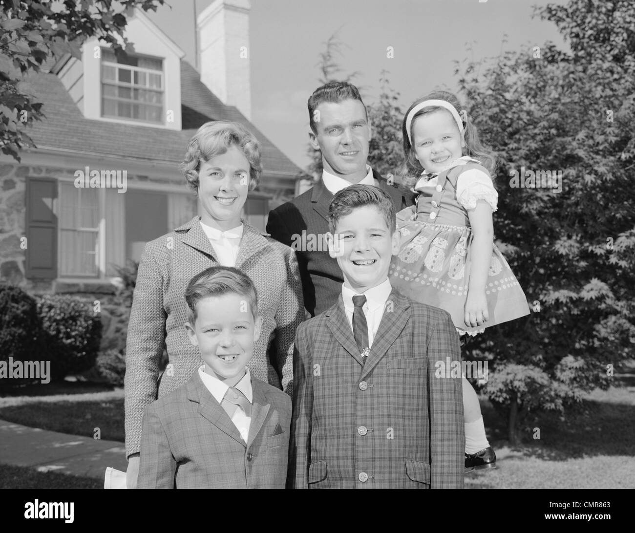 1960 Portrait de famille Père Mère DEUX FILS ET SA FILLE EN FACE DE SUBURBAN HOUSE LOOKING AT CAMERA Banque D'Images