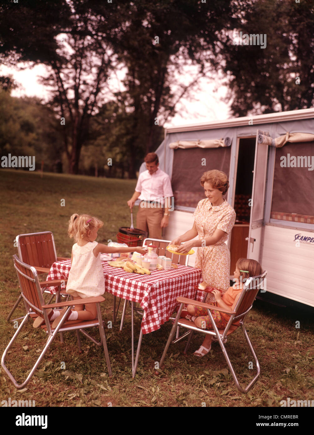 1960 RV CAMPING FAMILLE PÈRE MÈRE ET FILLES DE CUISSON TABLE PARAMÈTRE Banque D'Images