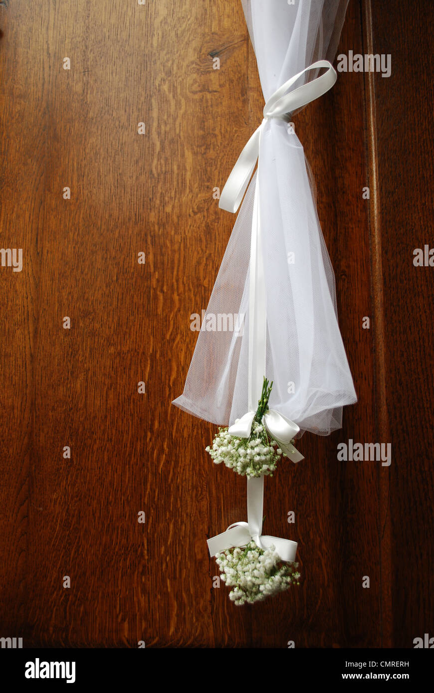 Fleurs de mariage blanc suspendu à l'avant porte de bois d'une église Banque D'Images