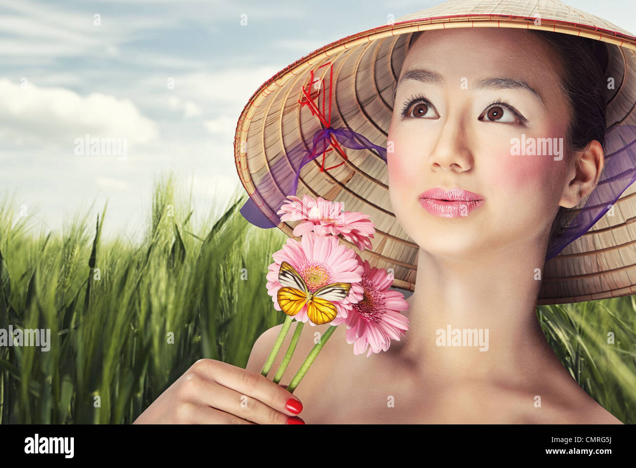 Belle fille vietnamienne dans un chapeau traditionnel est holding Flowers Banque D'Images