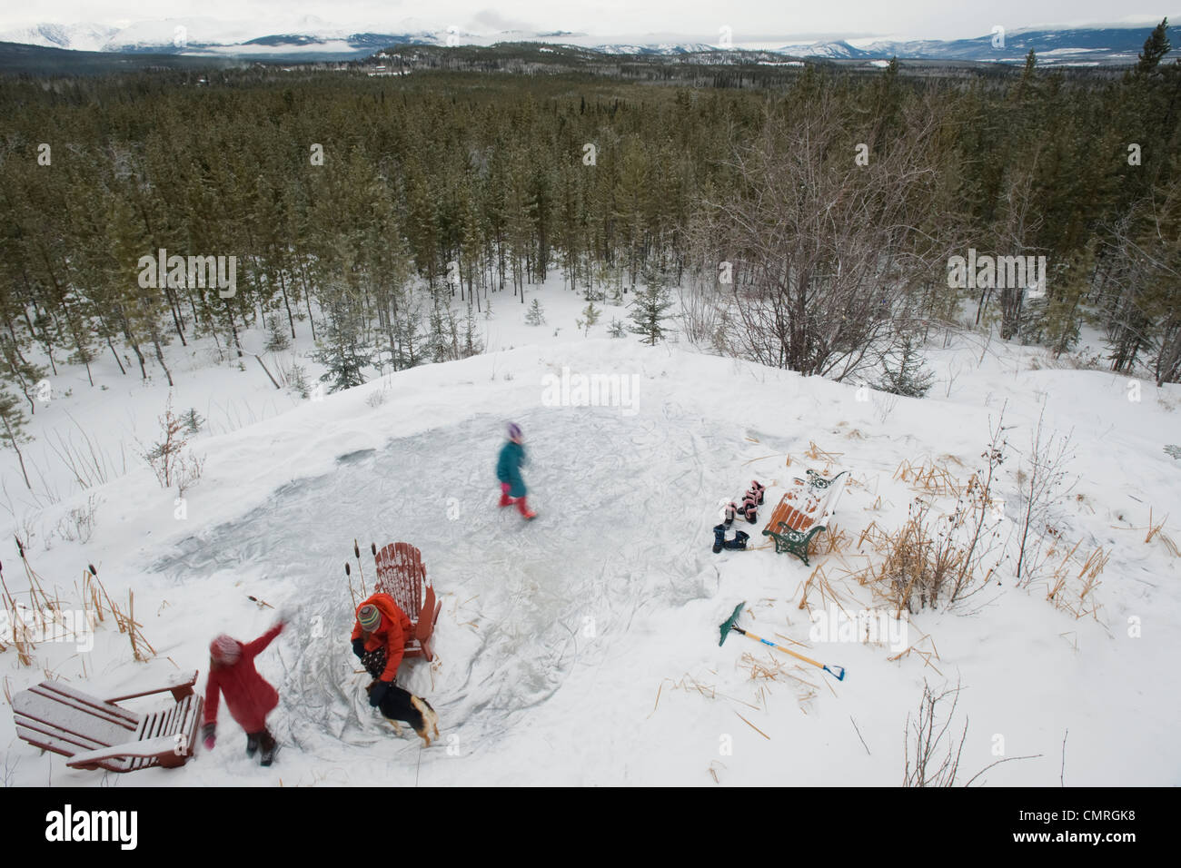 Vue aérienne de trois soeurs patinage sur l'étang d'arrière-cour en hiver, Whitehorse, Yukon Banque D'Images