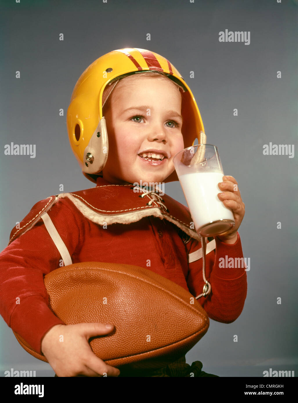 Années 1950 Années 1960 BOY DRINKING GLASS PORTER LAIT FOOTBALL HELMET ÉPAULETTES Banque D'Images