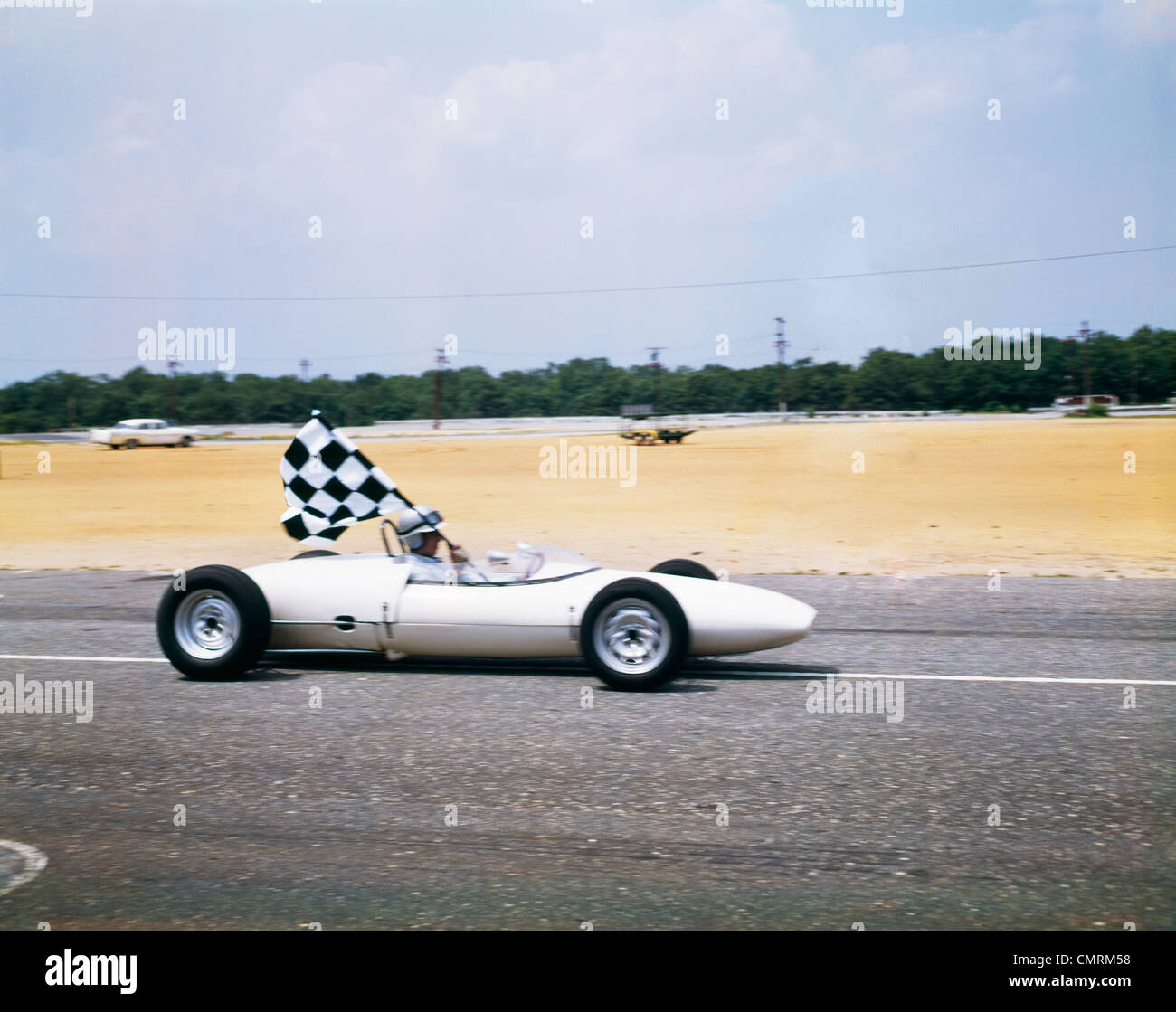 1960 conducteur de voiture de course dans LOTUS FORD VOITURE PRENANT TOUR D'HOLDING drapeau à damiers RETRO Banque D'Images