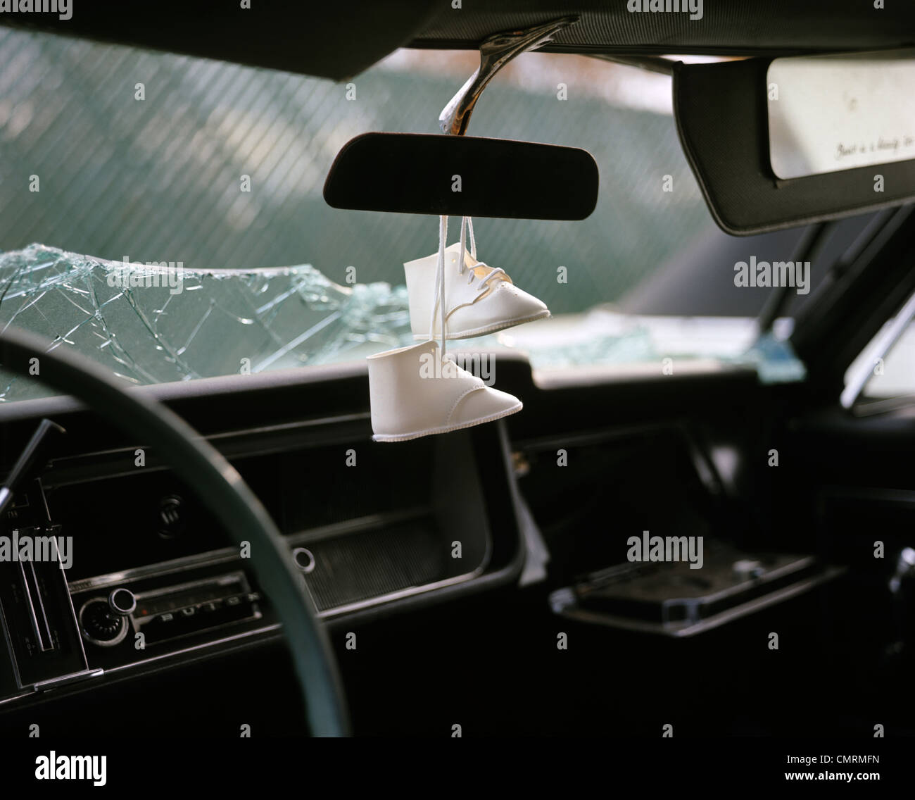 Paire de chaussures de bébé blanc se balance au rétroviseur intérieur de  voiture accidentée avec verre brisé le pare-brise des années 1970 Photo  Stock - Alamy