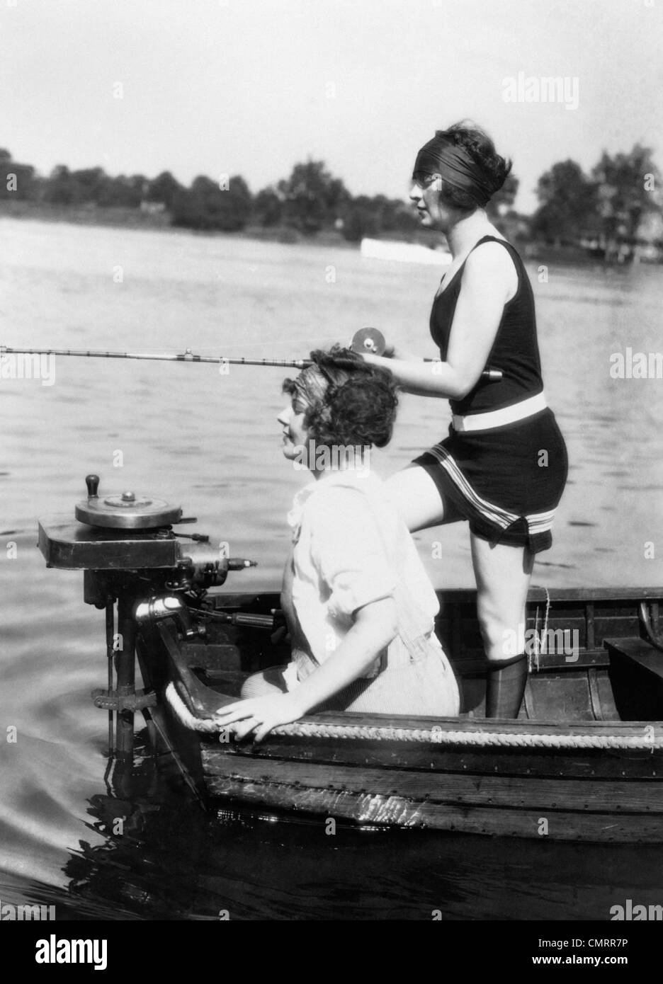 Années 1920 Années 1930 DEUX FEMMES DE PÊCHE ARRIÈRE DU PETIT BATEAU À MOTEUR AVEC UNE FEMME D'EXTÉRIEUR WIFI WEARING BATHING SUIT Banque D'Images