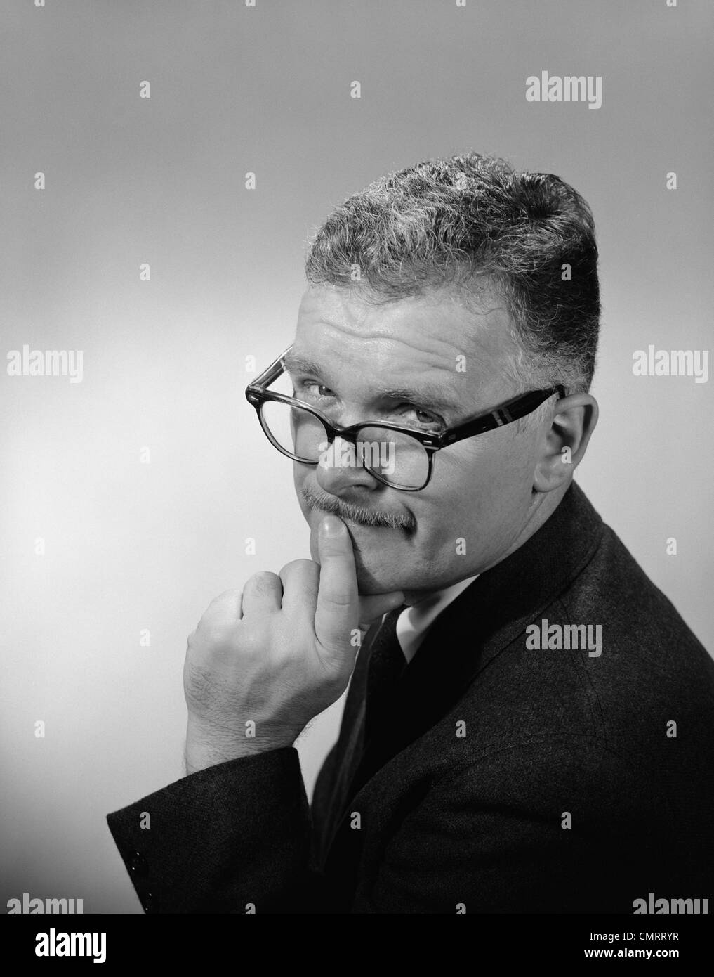 Années 1950 Années 1960 L'HOMME D'ÂGE MOYEN PORTANT DES LUNETTES SUR LE NEZ FAIBLE EXPRESSION DU VISAGE INTERROGATEUR Banque D'Images