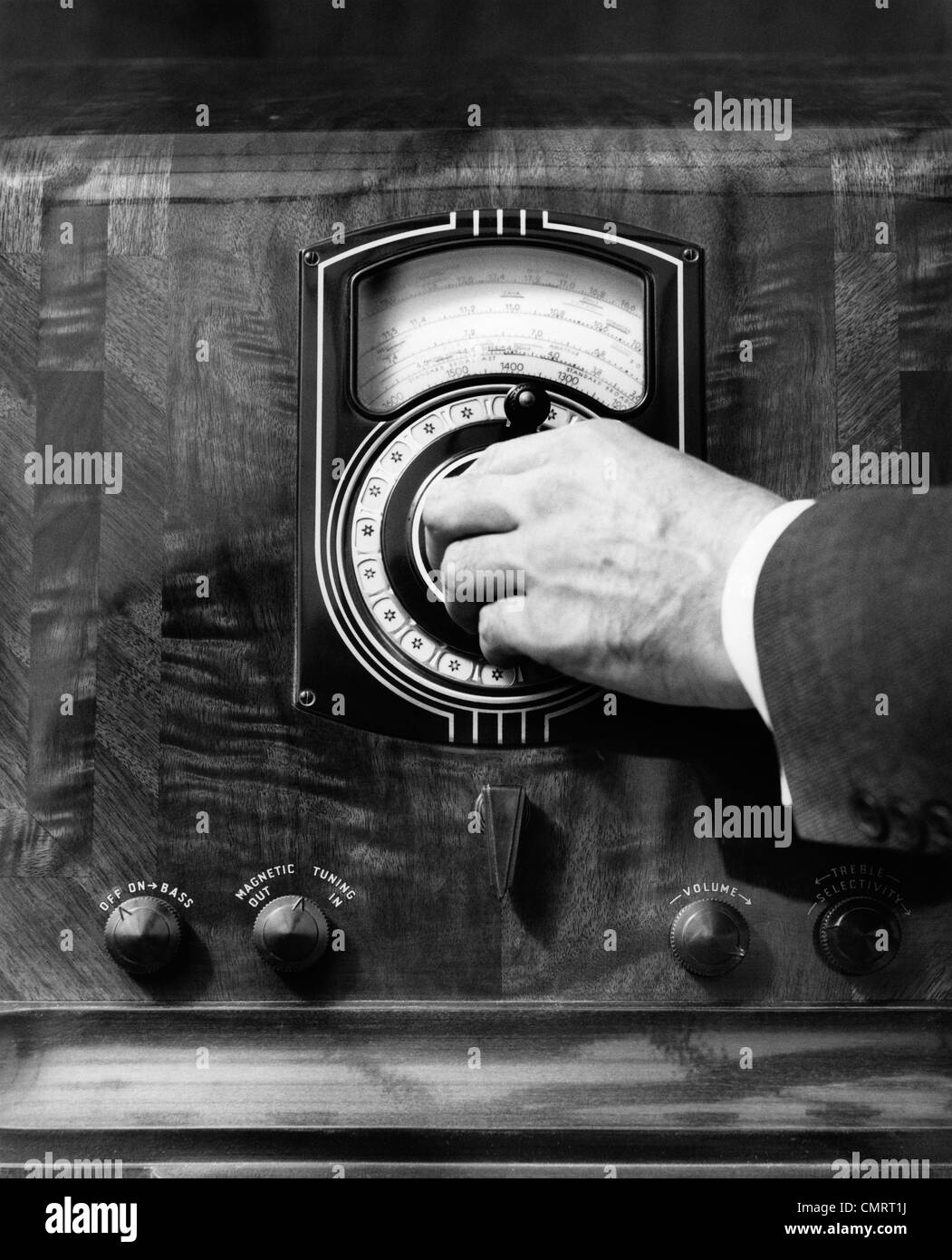 Années 1930 CLOSE UP LA MAIN DE L'HOMME EN TOURNANT LE CADRAN RADIO Banque D'Images