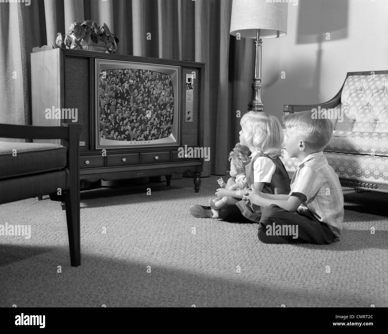 1960 Frère et soeur ASSIS SUR LE PLANCHER DU SALON en regardant la télé Banque D'Images