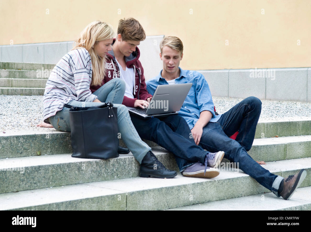 Trois étudiants assis sur stonestairs avec portable Banque D'Images