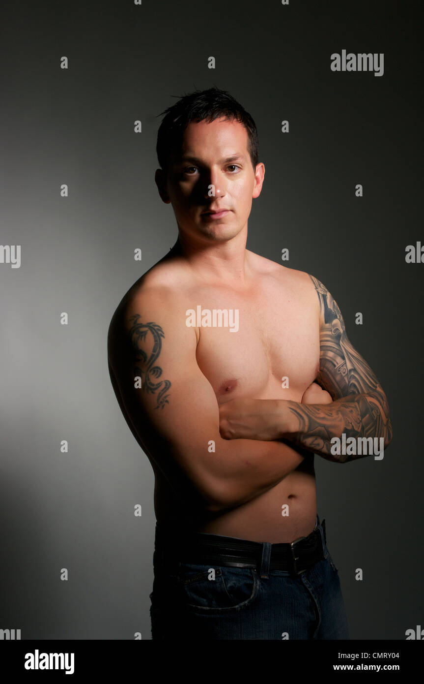 Un homme torse nu se tient dans l'éclairage à contraste élevé avec les bras  croisés Photo Stock - Alamy