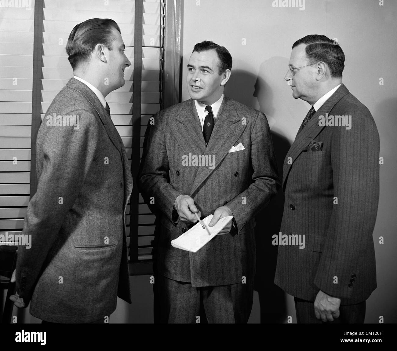 Années 1940 Années 1950 Trois hommes d'vendeurs parlent ensemble IN OFFICE Banque D'Images