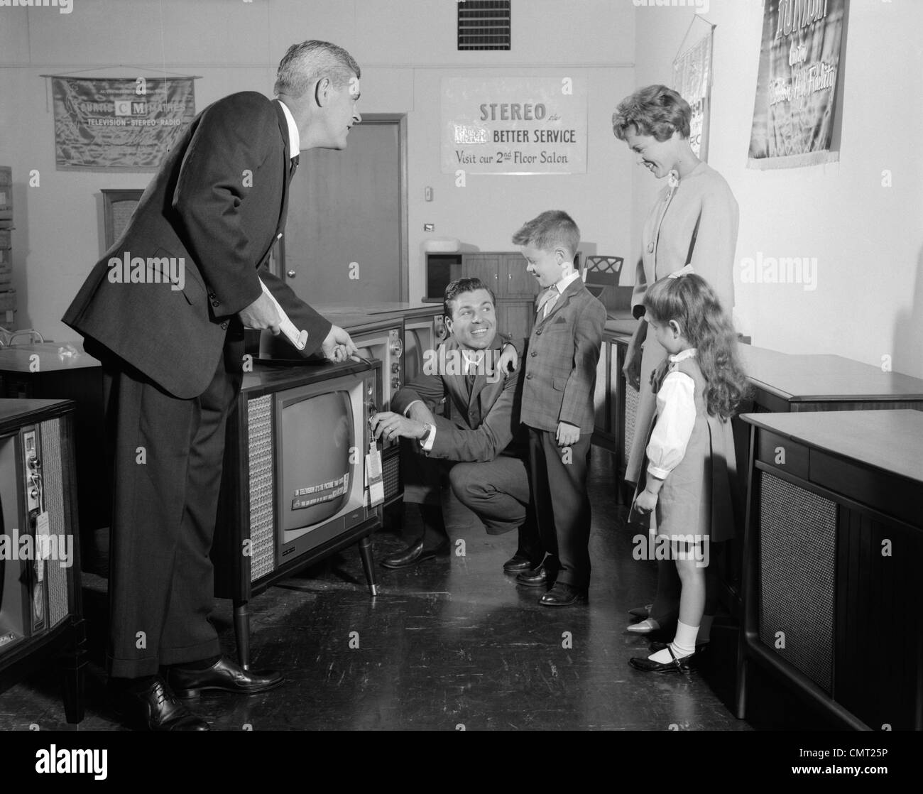1960 FAMILLE EN ESSAYANT D'EXPOSITION TV SET QUAND VENDEUR MONTRES Banque D'Images 1960 FAMILLE EN ESSAYANT D'EXPOSITION TV SET QUAND VENDEUR MONTRES Banque D'Images