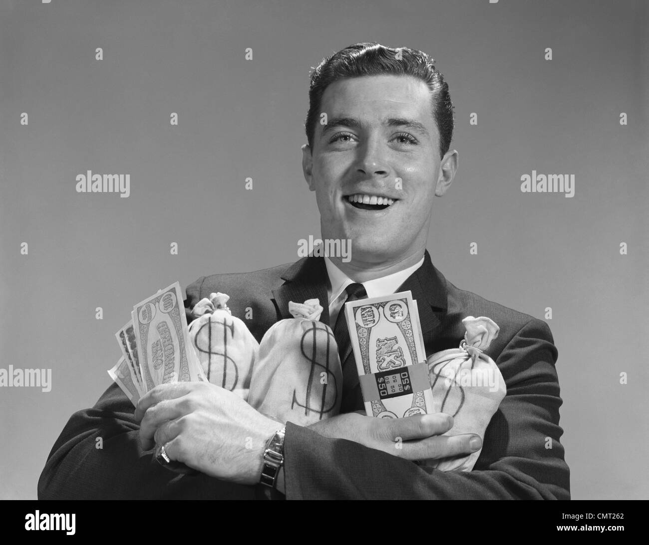 1960 SMILING MAN HOLDING des sacs d'ARGENT ET DE CADRES DE PAIEMENT Banque D'Images