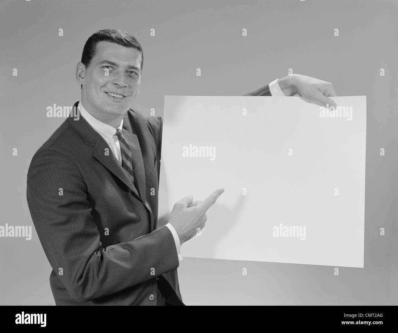 1960 SMILING MAN POINTING DE BLANK POSTER LOOKING AT CAMERA Banque D'Images