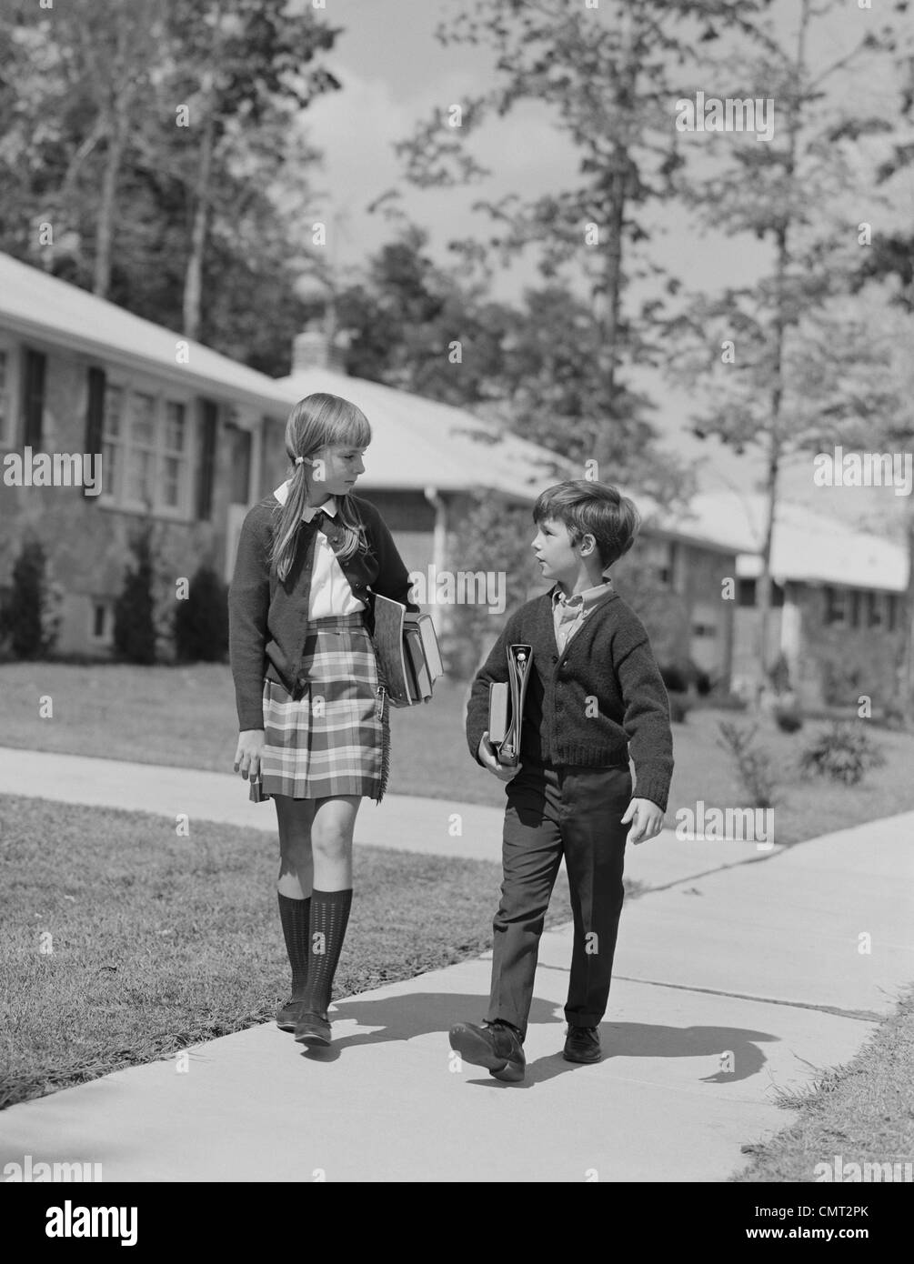 1960 Garçon Fille portant des livres à l'ÉCOLE À PIED EN BANLIEUE Banque D'Images