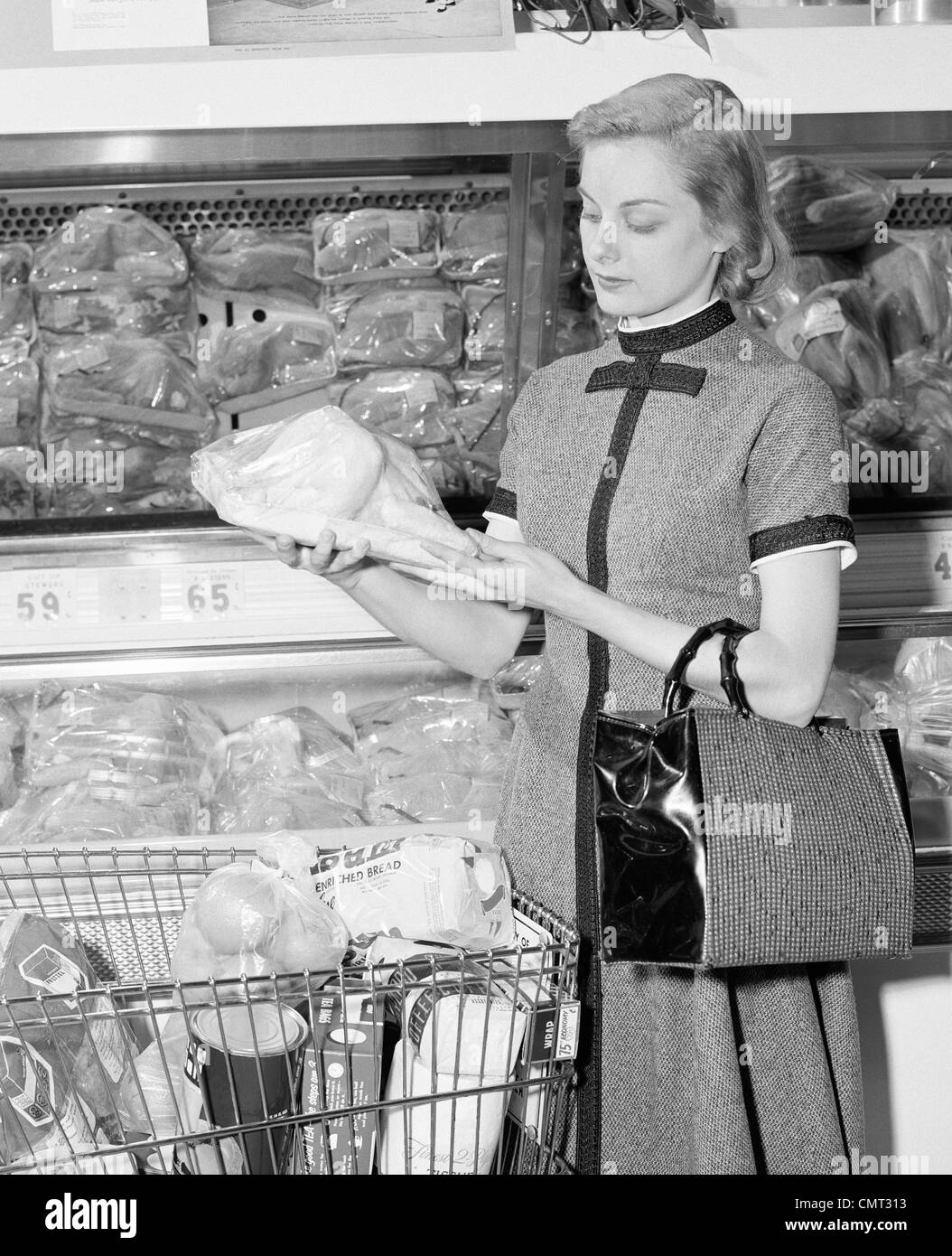 Années 1950 Années 1960 Femme blonde en sélectionnant les volailles en supermarché Banque D'Images