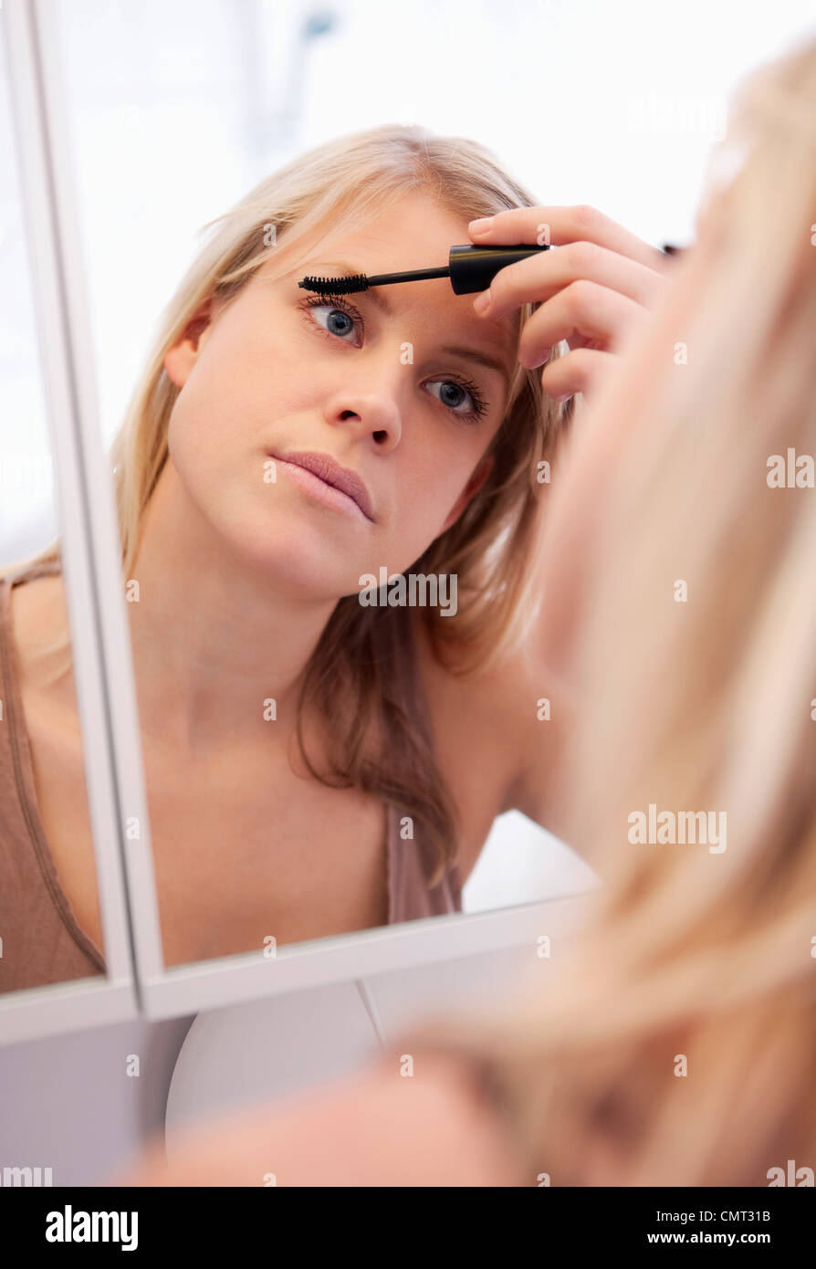 Femme debout dans la salle de bains pour se maquiller Banque D'Images
