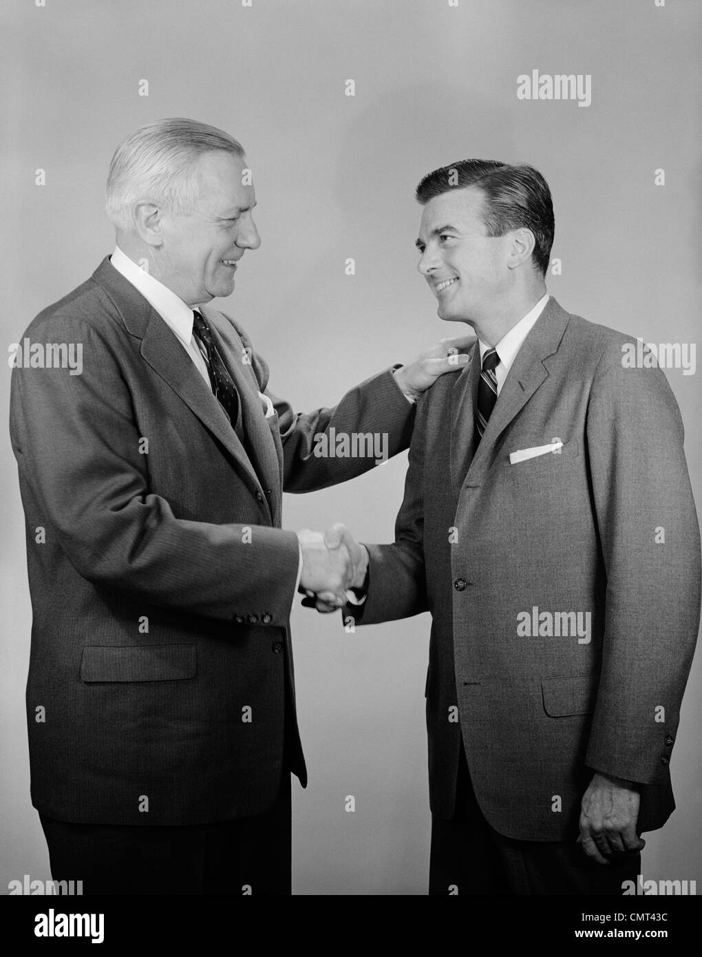 Années 1950, LES PERSONNES ÂGÉES ET LES JEUNES BUSINESS MEN SHAKING HANDS Banque D'Images